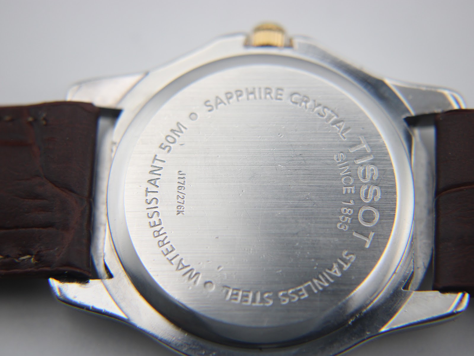 Close-up of the stainless steel case back of the Tissot PR 50, showing "sapphire crystal 50m waterresistant" and "J176/276K".