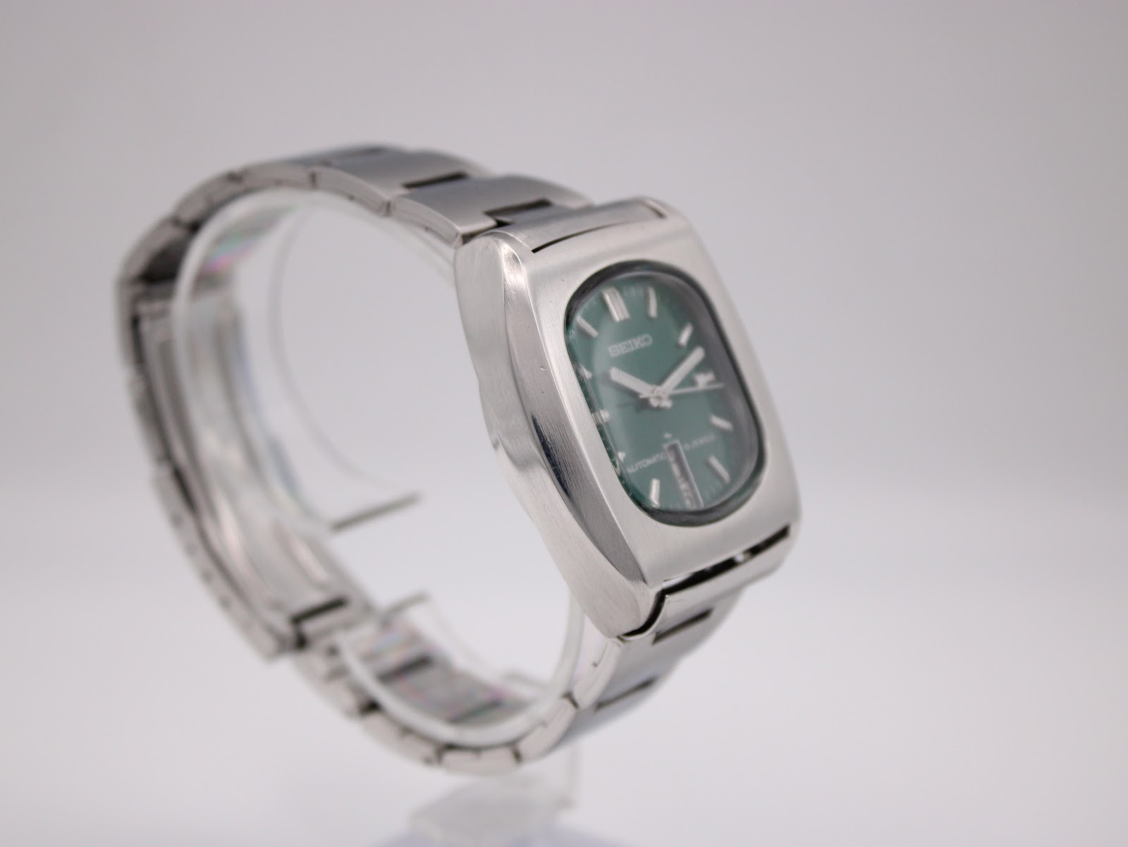 Angled view of the Seiko 7006-5070 watch, highlighting the case shape and bracelet, on a clear display stand.