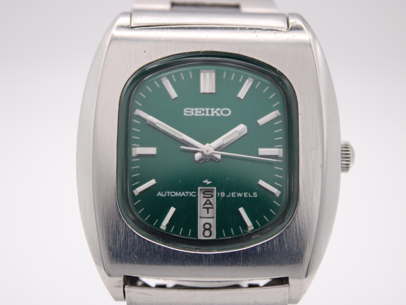 Close-up of the vibrant green dial of the Seiko 7006-5070, showing applied baton markers, day/date window, and 'SEIKO AUTOMATIC 19 JEWELS' text.