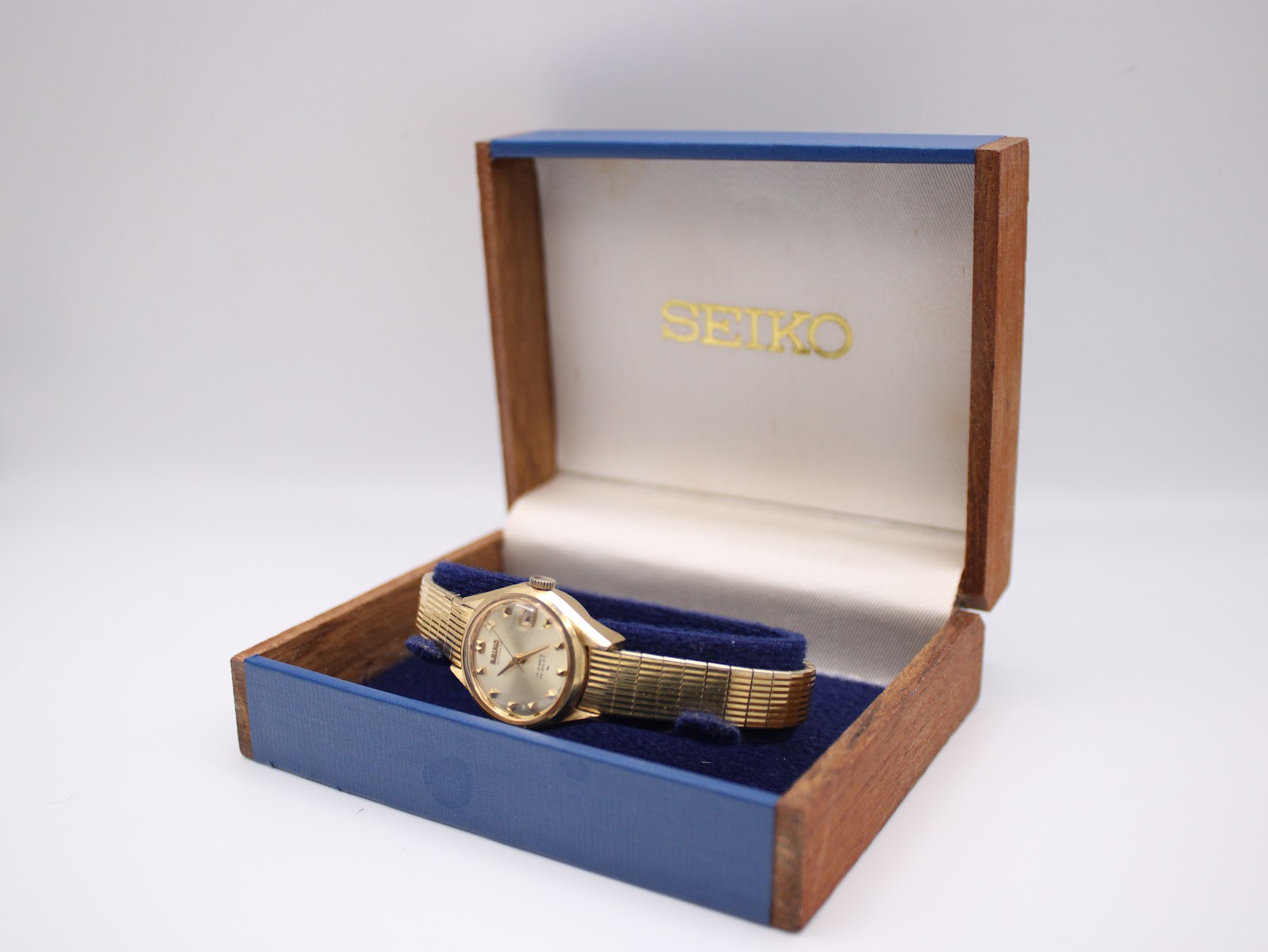 Front view of vintage Seiko 2205-0250 automatic watch with champagne sunburst dial, gold baton indices, and date at 3 o'clock.