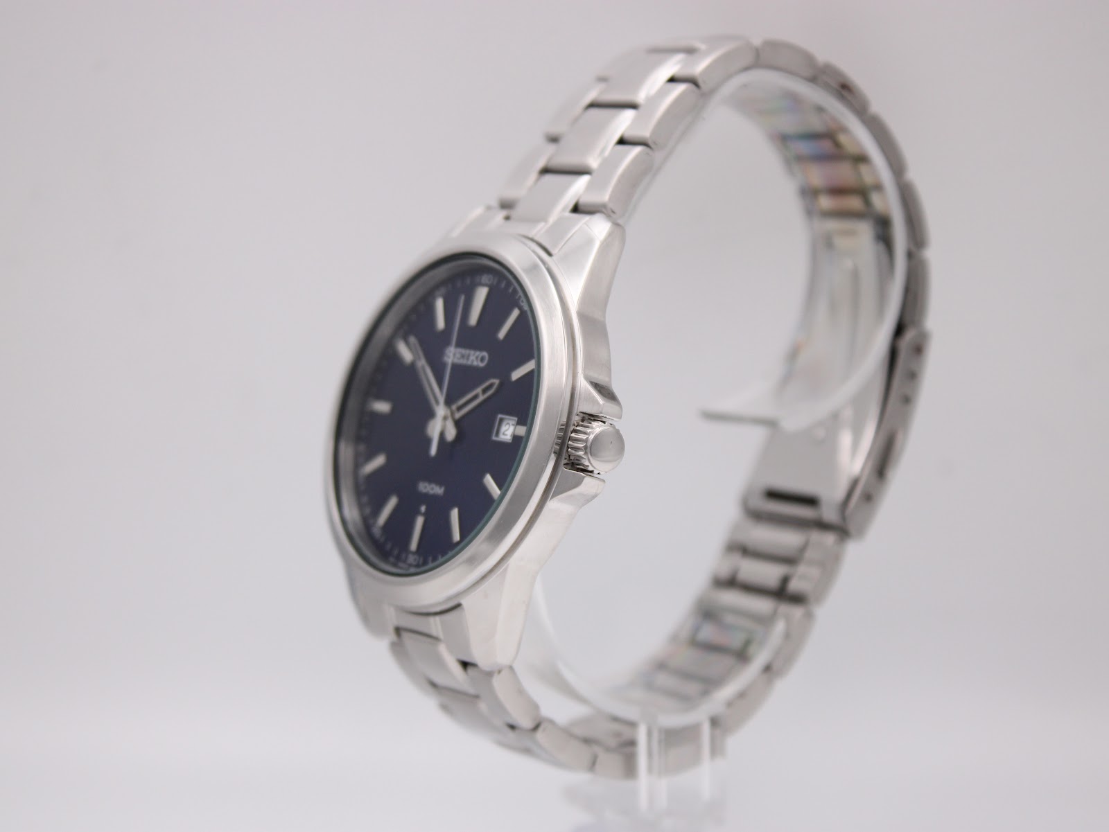 Close-up of Seiko push-button deployant clasp with engraved Seiko logo, showing mixed brushed and polished stainless steel finish