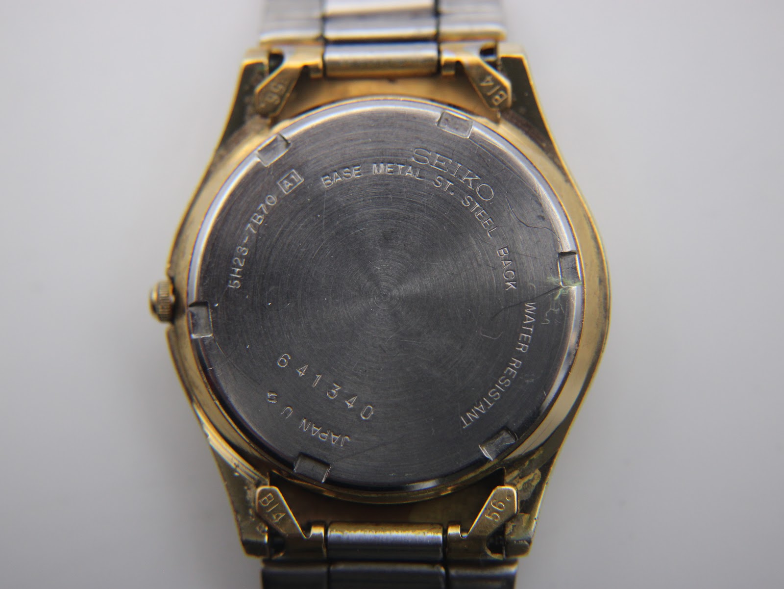 Close-up of the stainless steel case back, showing model number 5H23-7B70, serial 641340, and "Water Resistant" text.