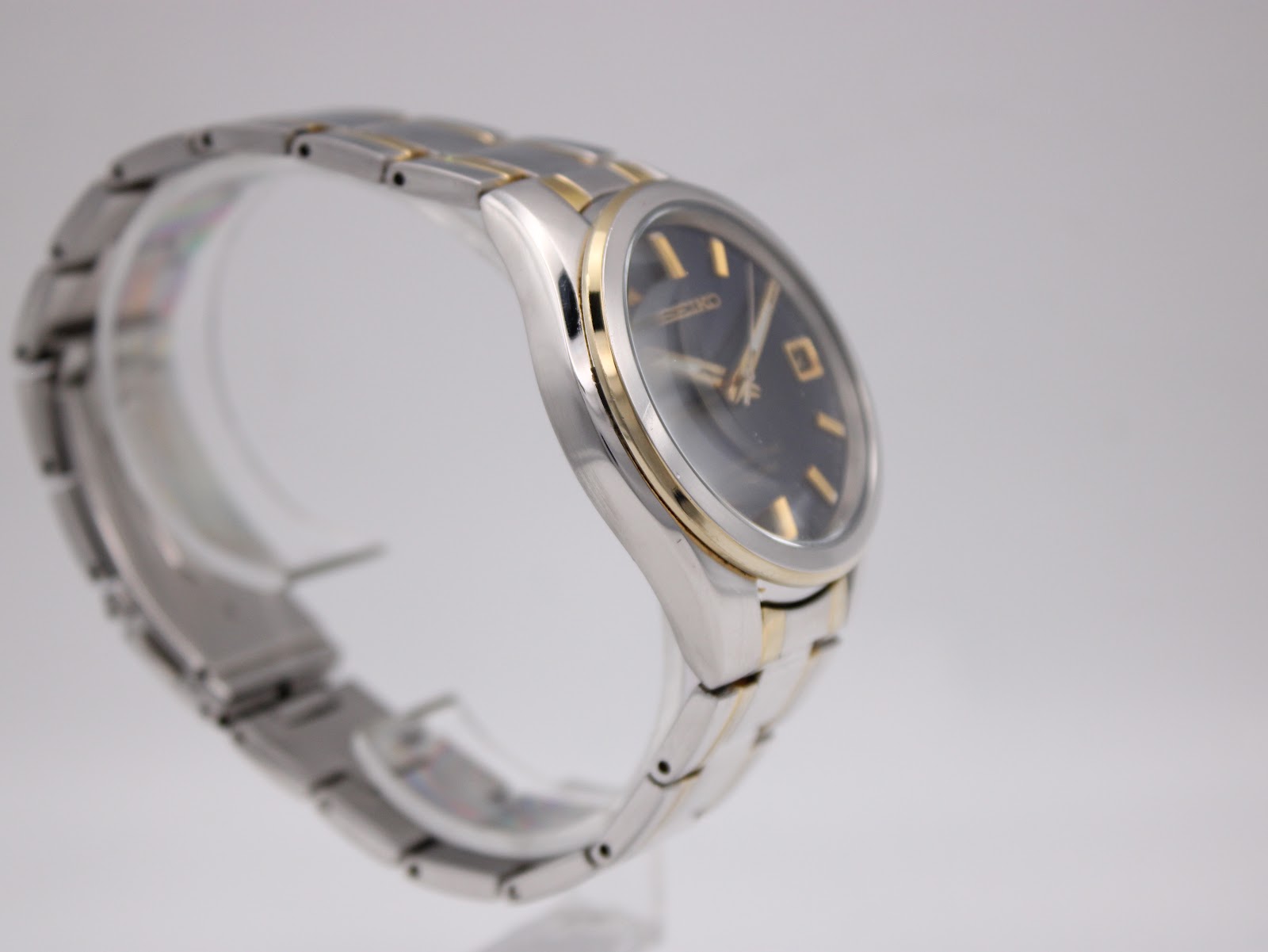 Another angled side view of the Seiko watch, focusing on the profile of the case and the gold-tone bezel.