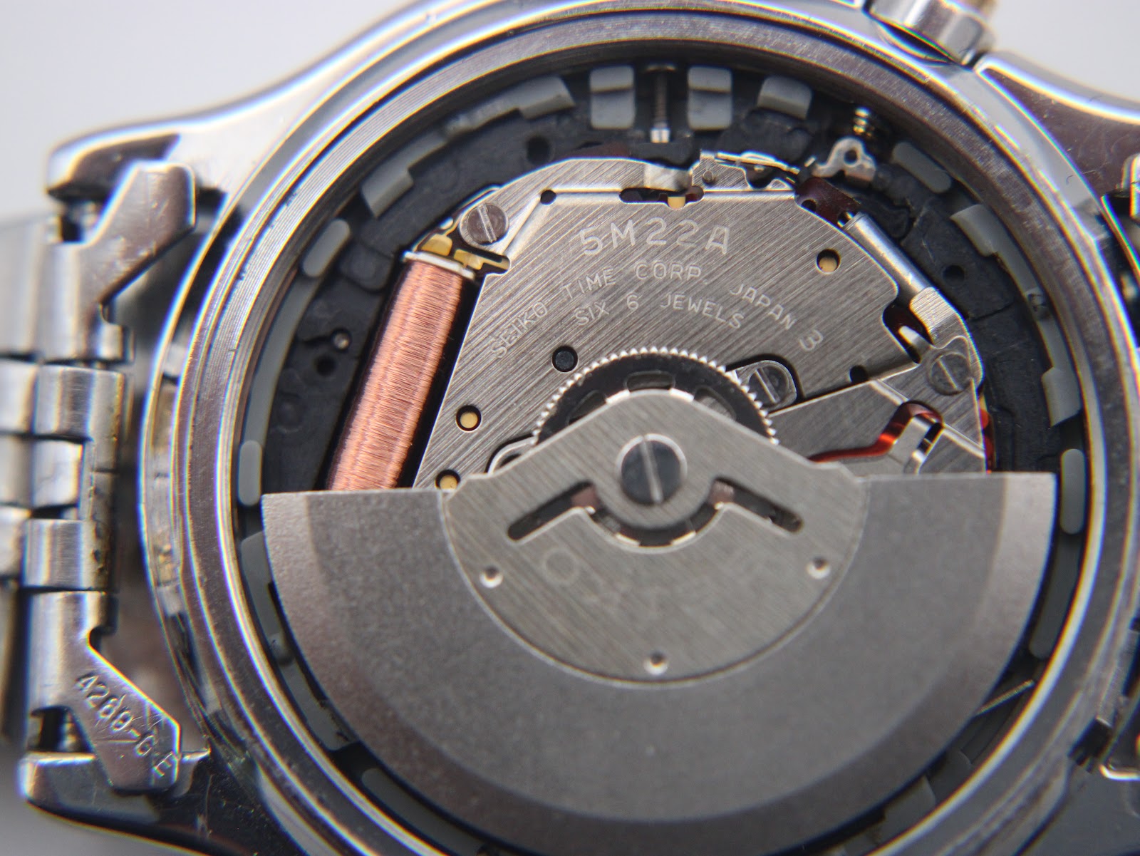 Macro shot of the Seiko 5M22A Kinetic movement inside the watch, showing the rotor and coil.