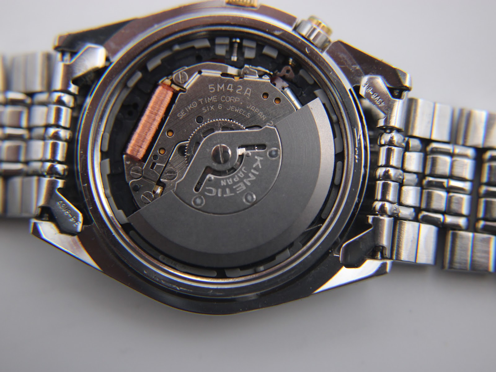 Detailed shot of the Seiko 5M42A kinetic movement inside the open case back, showing 'SEIKO TIME CORP. JAPAN SIX 6 JEWELS'.