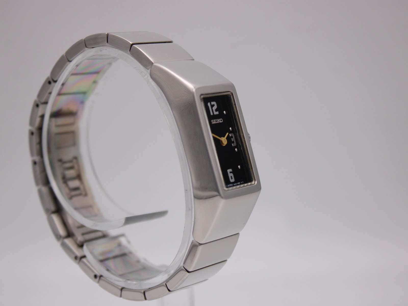 Angled front-left view of the Seiko watch on a display stand, highlighting the integrated bracelet design.
