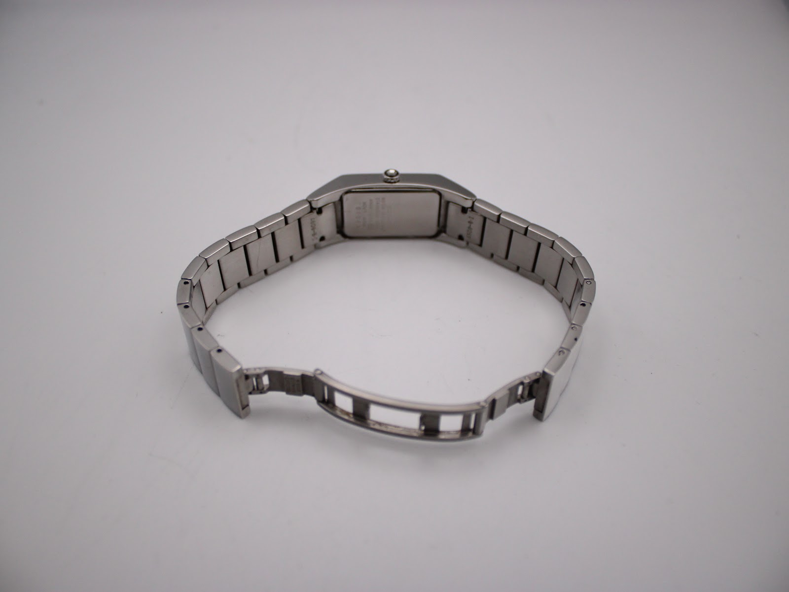 Rear view of the watch showing the integrated stainless steel bracelet with the deployant clasp open.