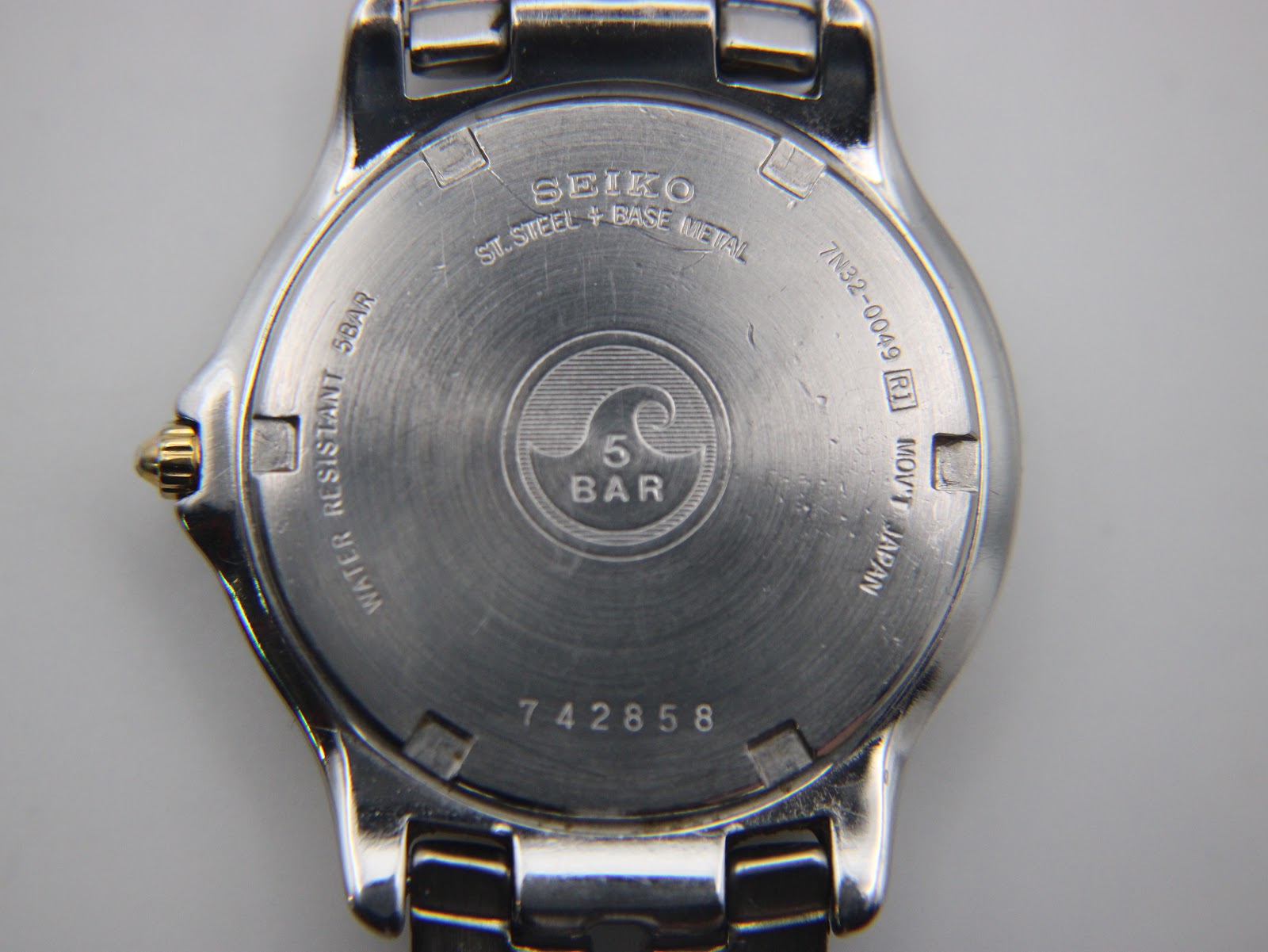Close-up of the watch case back, showing "SEIKO", "ST. STEEL + BASE METAL", "7N32-0049", serial "742858", and "WATER RESISTANT 5BAR".