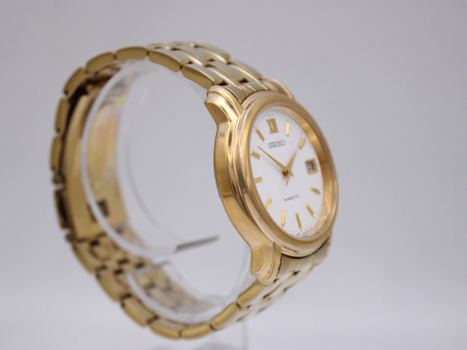 Another angled side view of the gold-tone Seiko kinetic watch, highlighting the integrated bracelet links and case curvature.