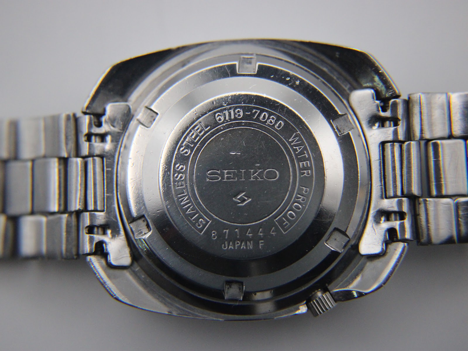 Close-up of the stainless steel case back, showing "SEIKO 6119-7080 STAINLESS STEEL WATER PROOF 871444 JAPAN F" engravings.