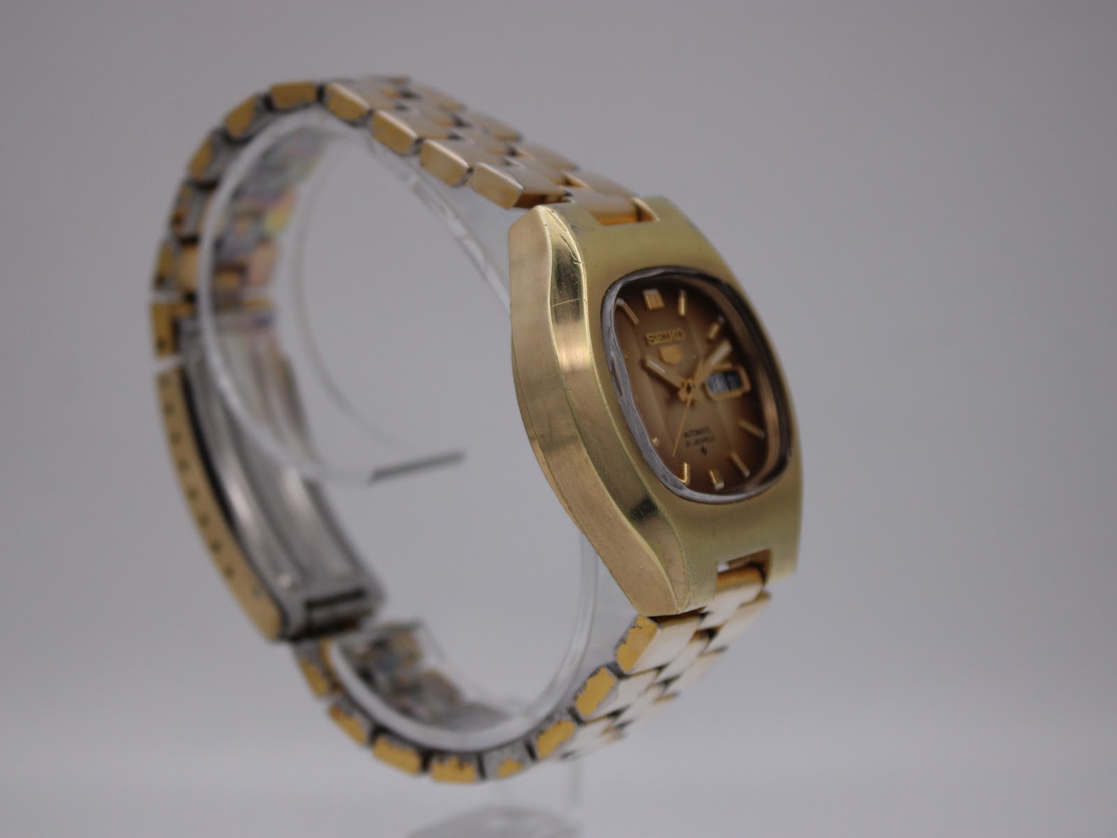 Close-up of the Seiko watch clasp, showing the signed logo and gold plating wear.