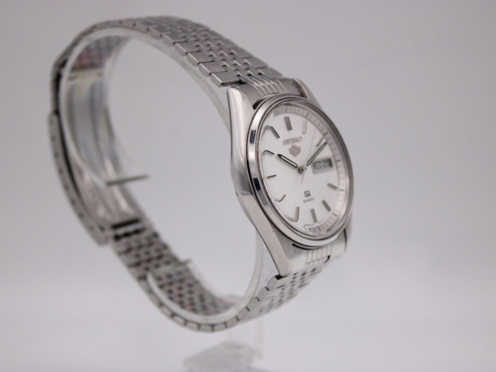 Another angled side view of the Seiko SQ on a watch stand, highlighting the bracelet texture and case profile.