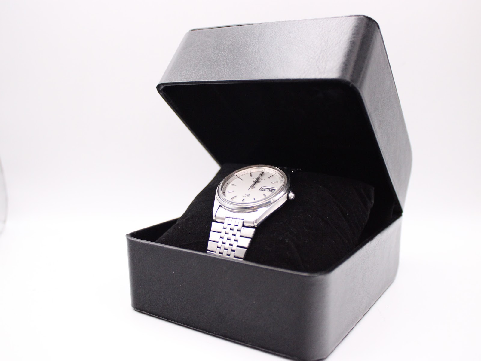Seiko SQ watch presented on a black velvet cushion inside a sleek black display box.