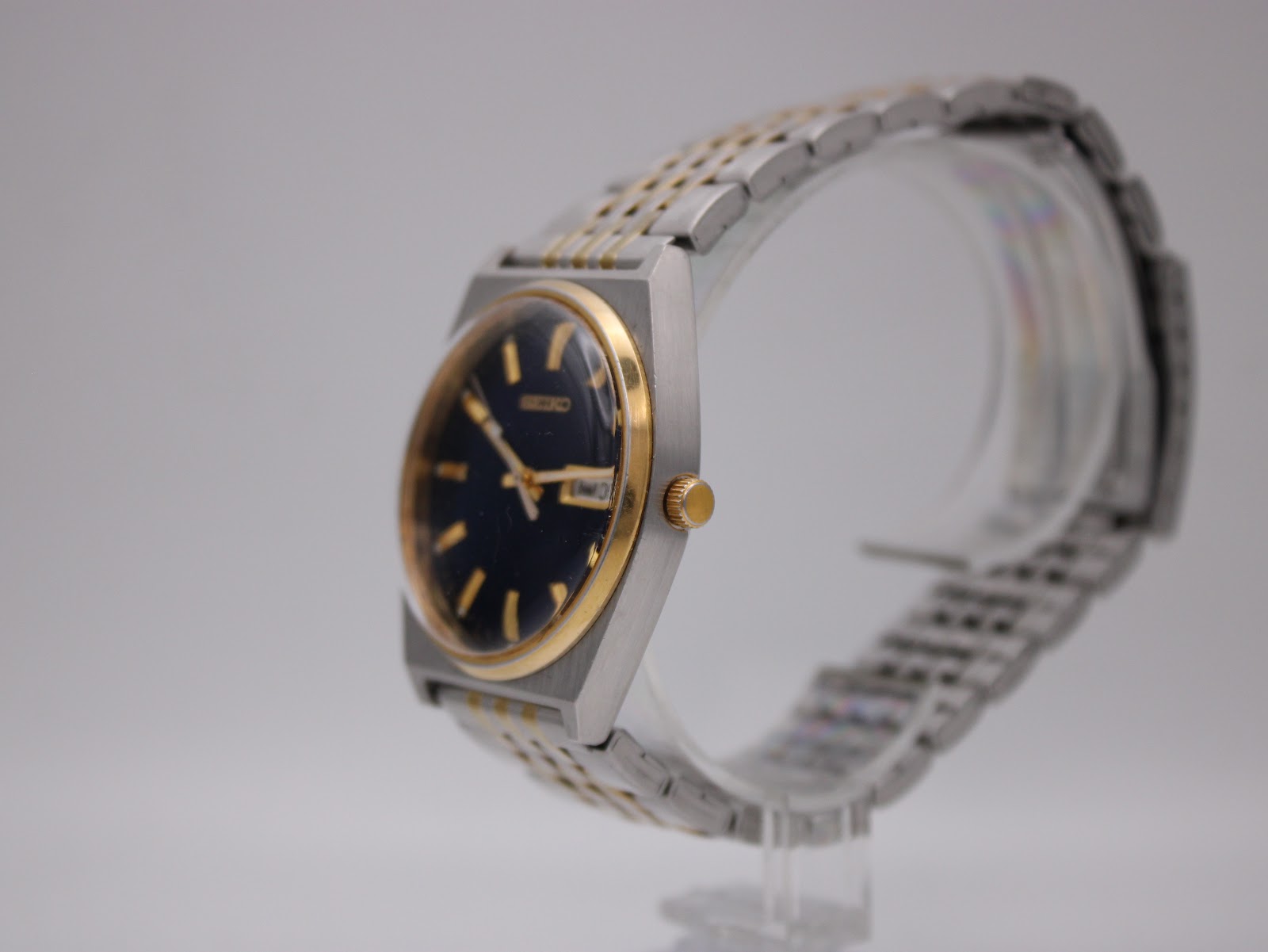 Angled view of the Seiko V743-9020 vintage quartz watch on a display stand, showing the right side and gold crown.