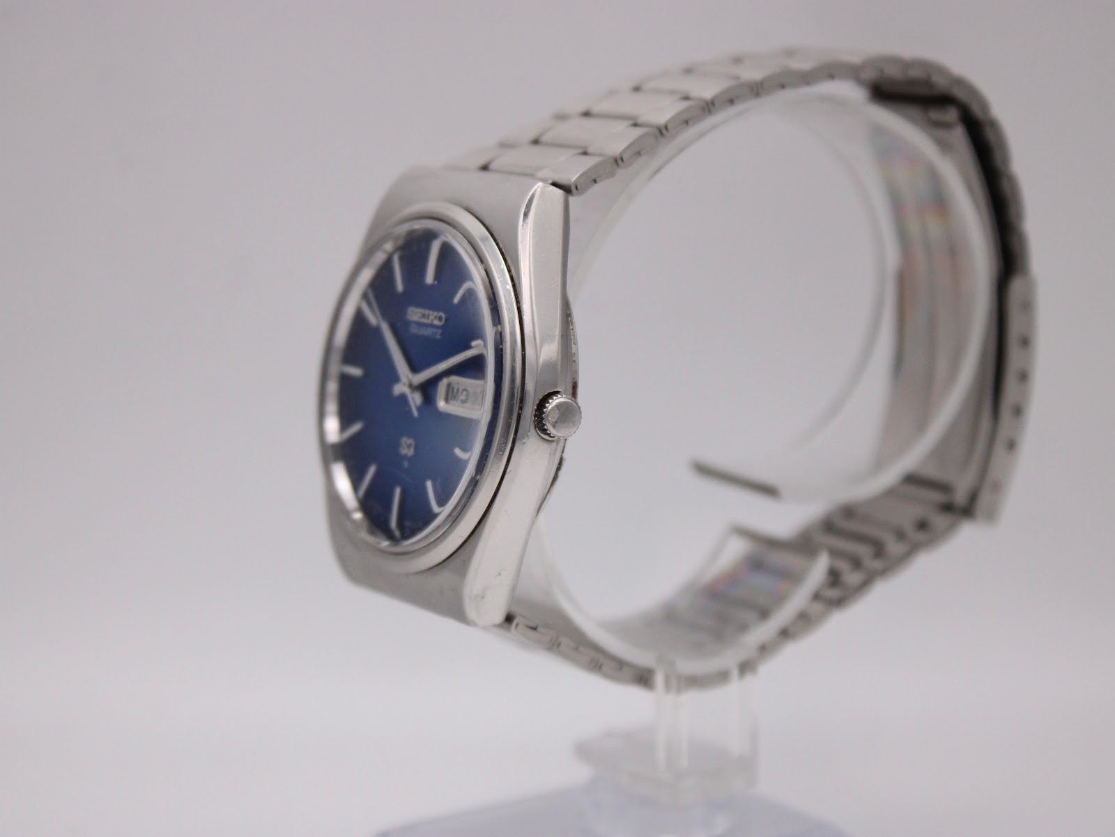 Side profile of the vintage Seiko quartz watch on a stand, highlighting the case shape and crown.