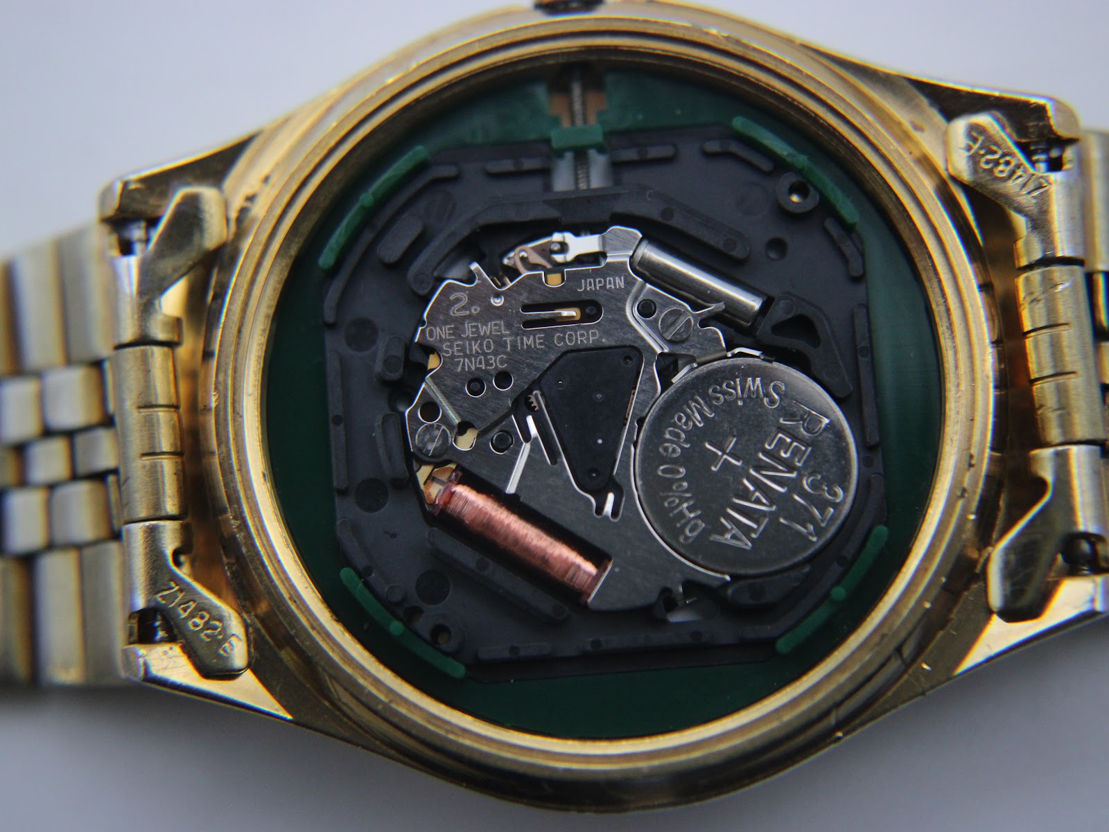Macro shot of the Seiko 7N43C quartz movement inside the open watch case, with a Renata battery visible.