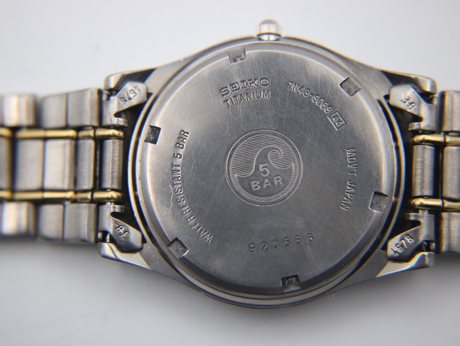 Close-up of the Seiko watch's case back, engraved with 'titanium' and 'water resistant 5 bar'.
