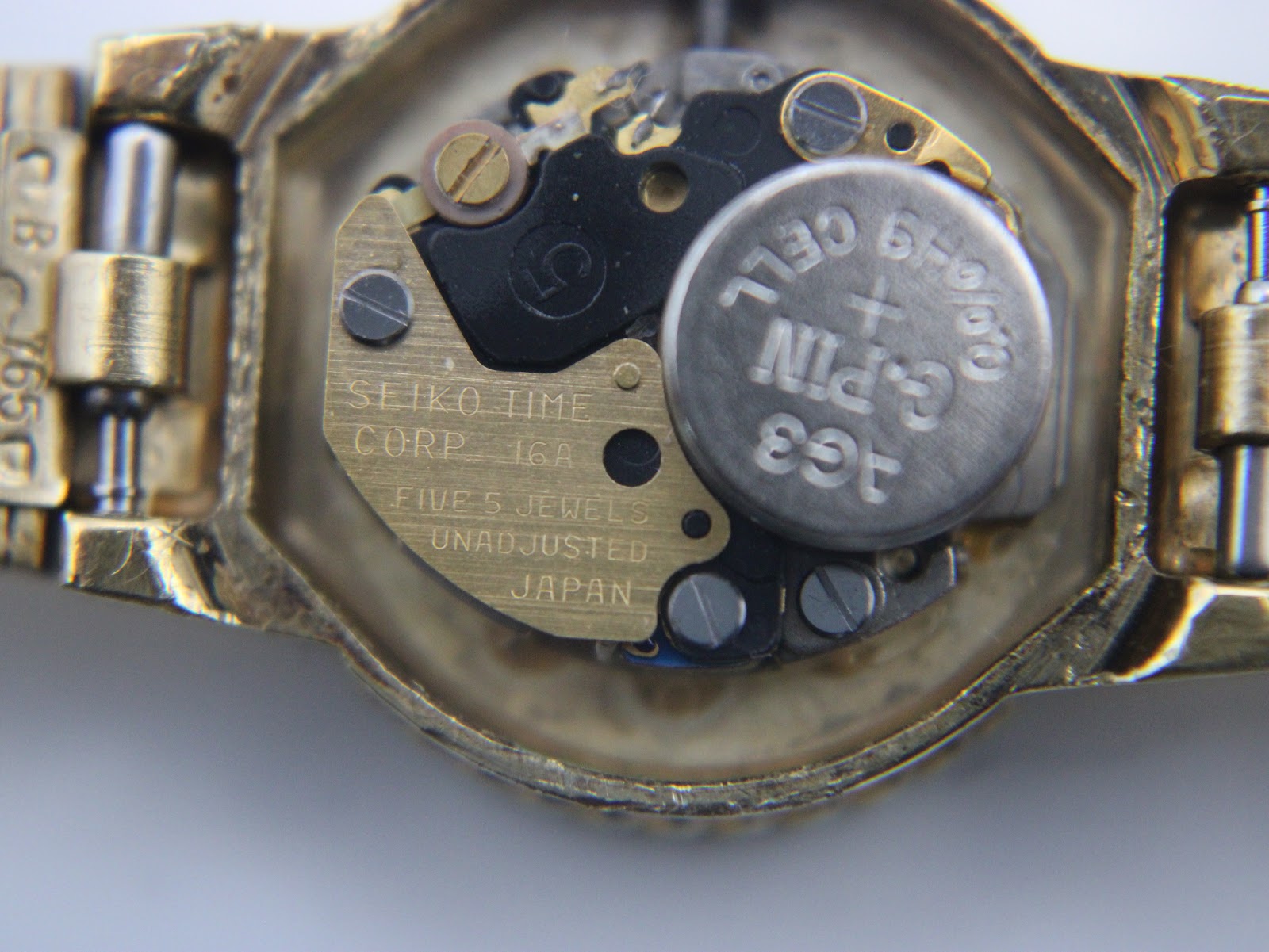 Macro shot of the quartz movement inside the watch, revealing the battery and 'SEIKO TIME CORP' markings.