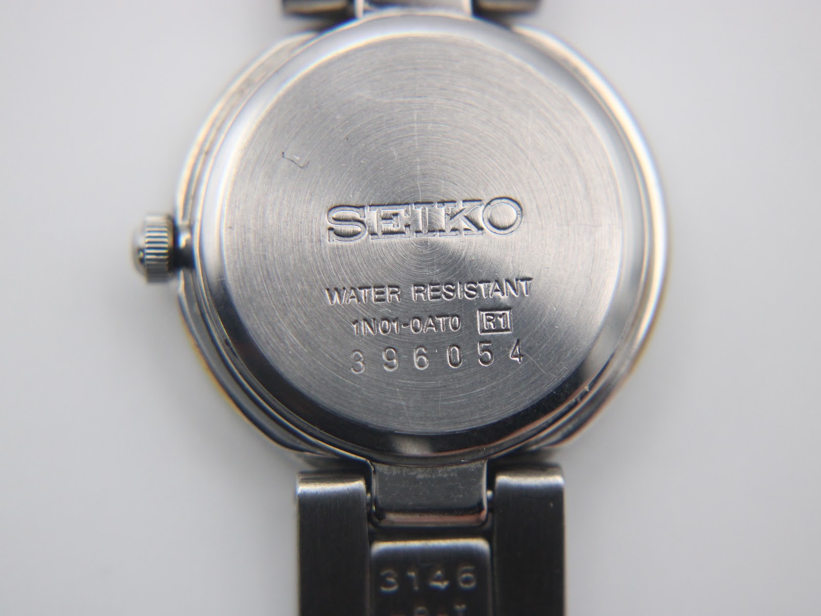 Close-up of the Seiko watch case back, showing 'Water Resistant', '1N01-0AT0', and serial number '396054'.