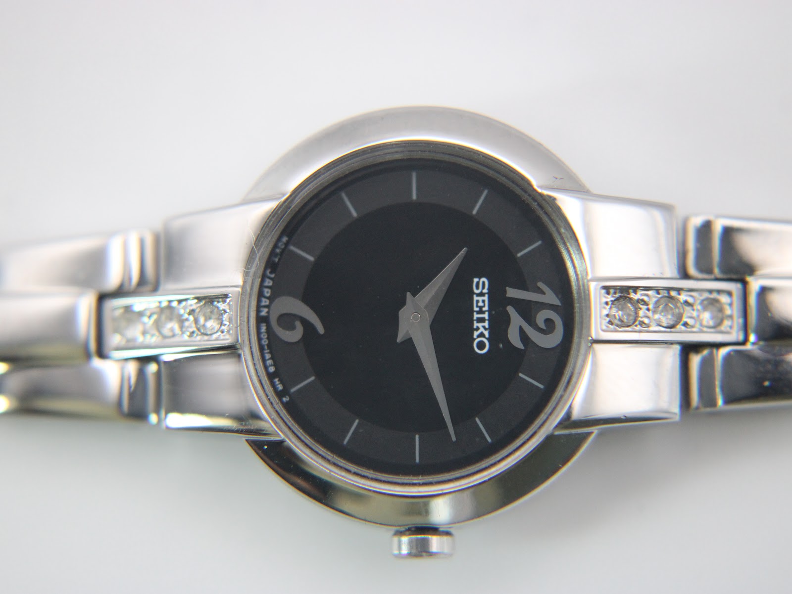 Detailed close-up of the black dial with silver-tone numerals at 12 and 6, baton indices, and Seiko logo.