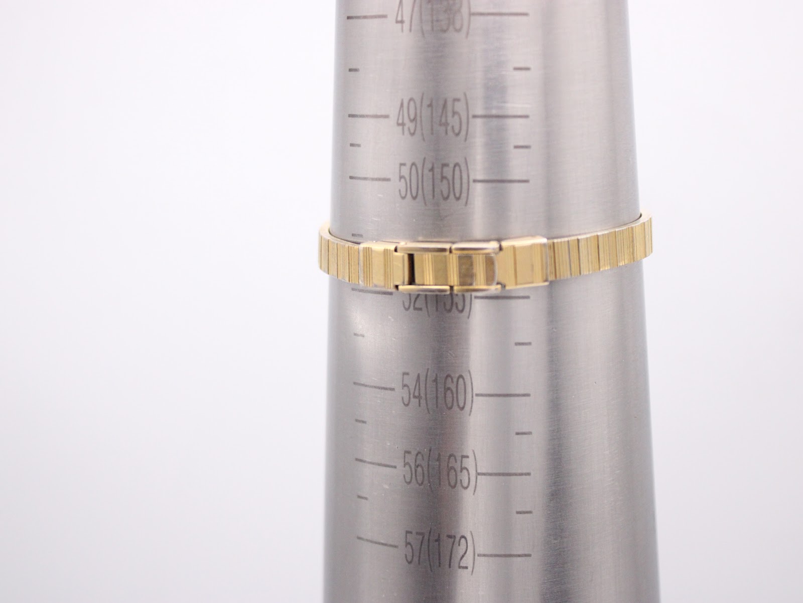 Close-up of the gold-tone expandable bracelet on a wrist sizing cone, showing the bracelet size is approximately 155mm / 15.5cm.