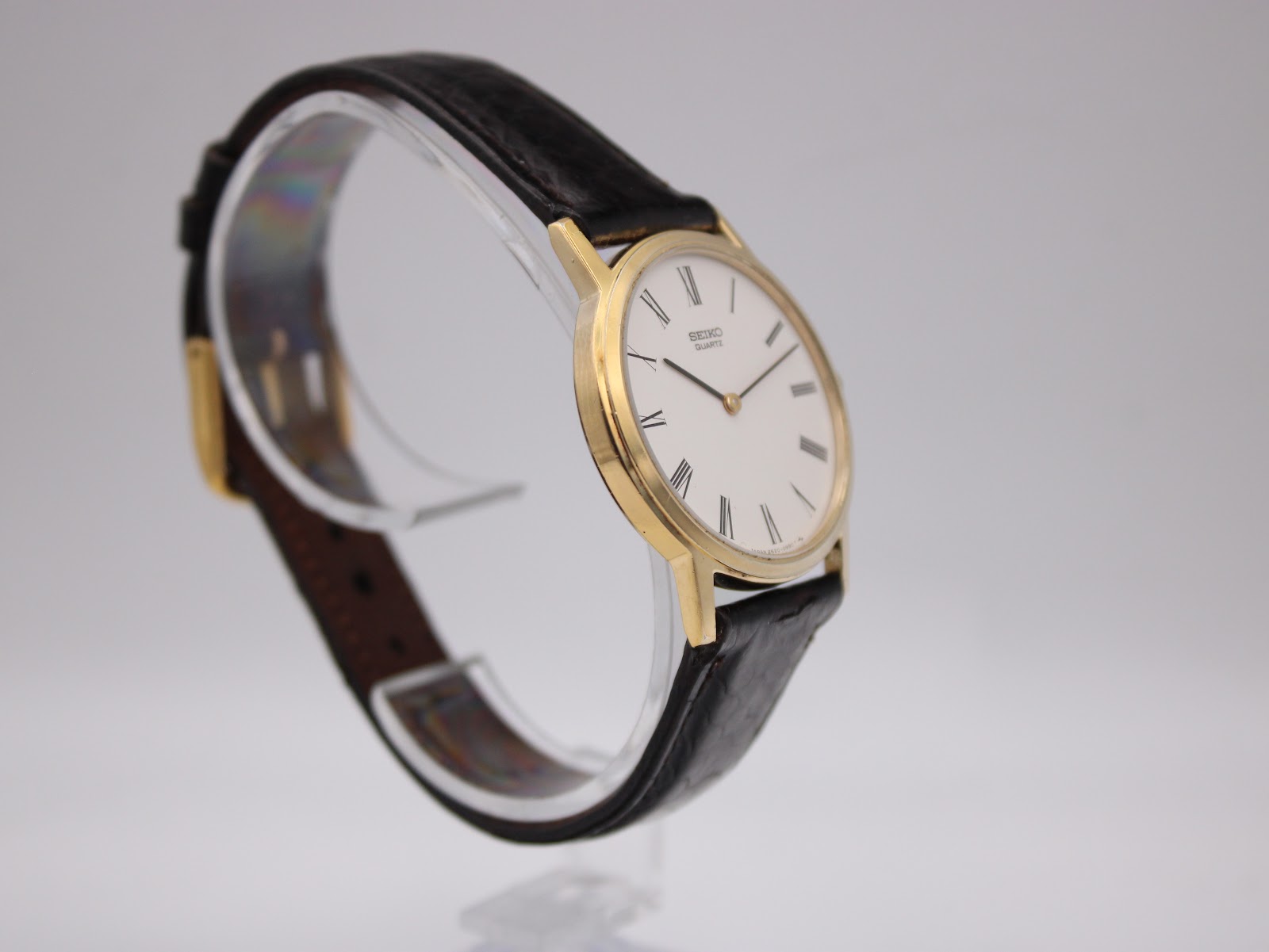 Angle view of the watch on a stand, showing the classic black leather strap.