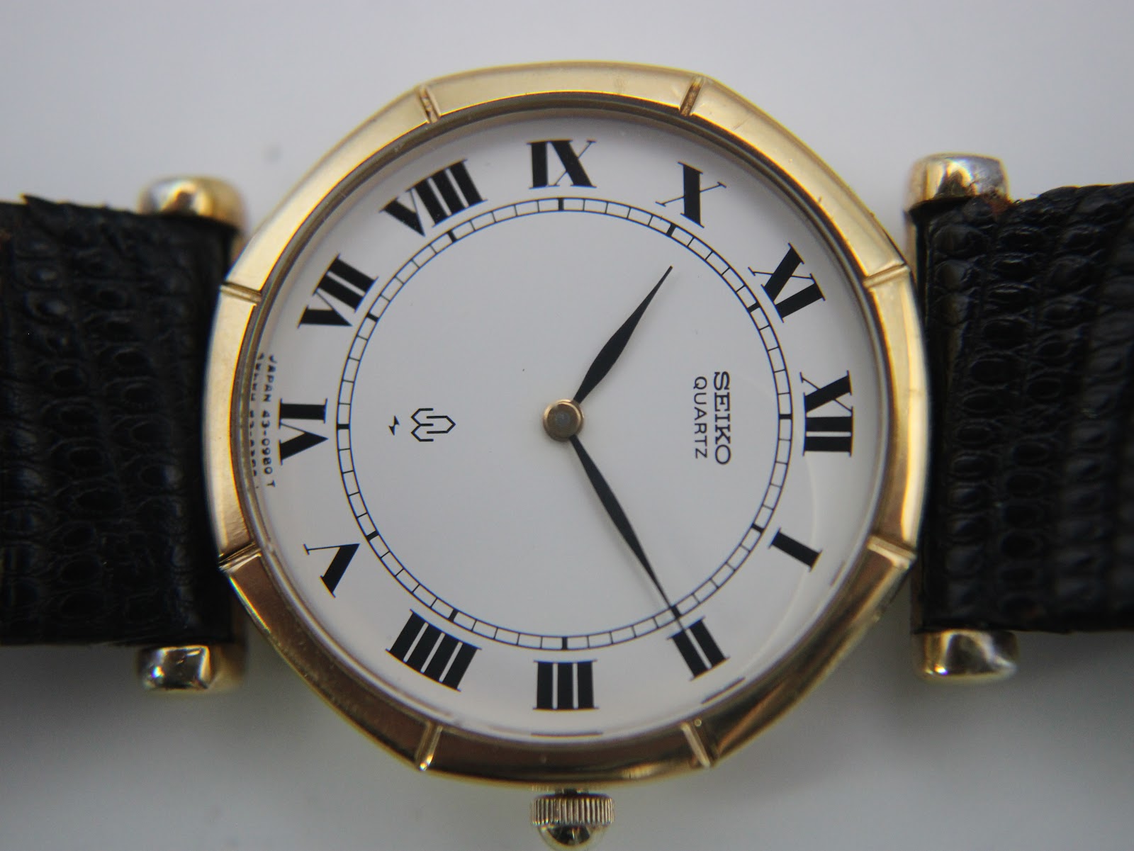 Detailed front view of the white Seiko dial, showing applied black roman numerals, railroad minute track, and 'SEIKO QUARTZ' branding.