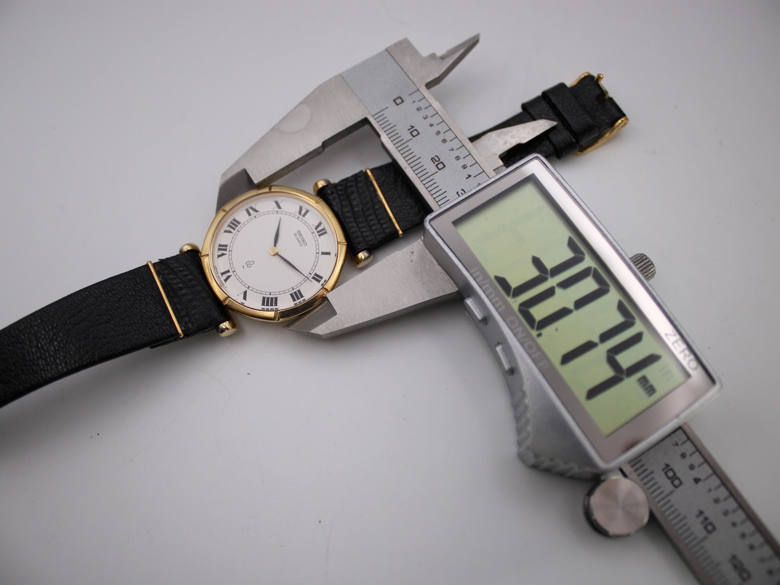Overhead view of the watch on its strap, with a digital caliper measuring the case diameter at precisely 30.74mm.