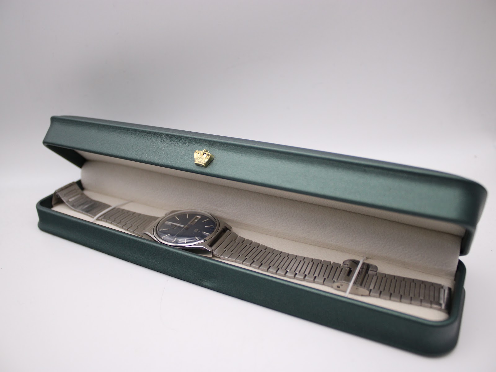The Seiko 7123-8430 watch resting inside a generic dark green presentation box, suggesting a neat storage option.