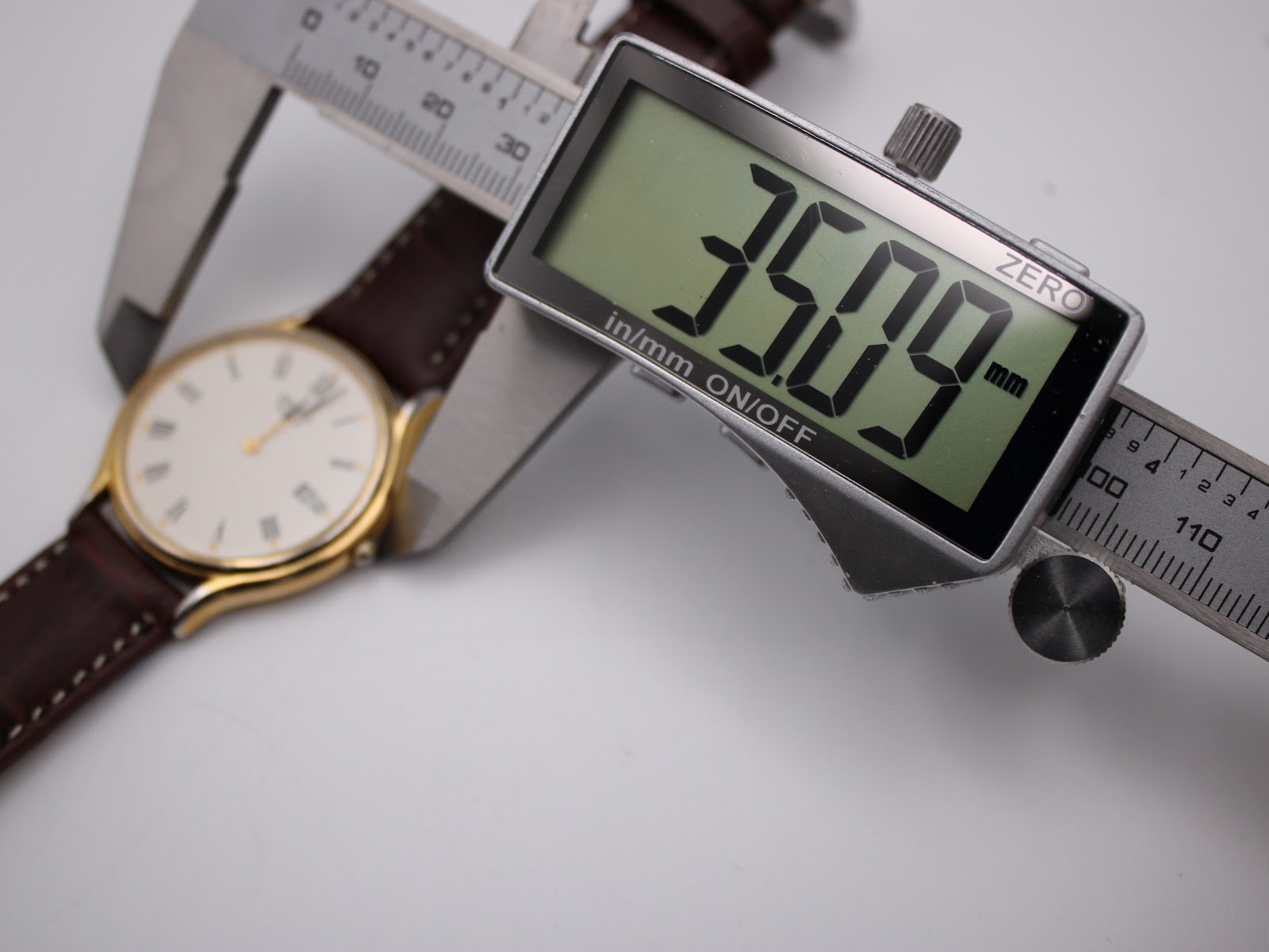 Digital caliper measuring the watch case diameter at 35.09mm, with the watch body visible in the background.