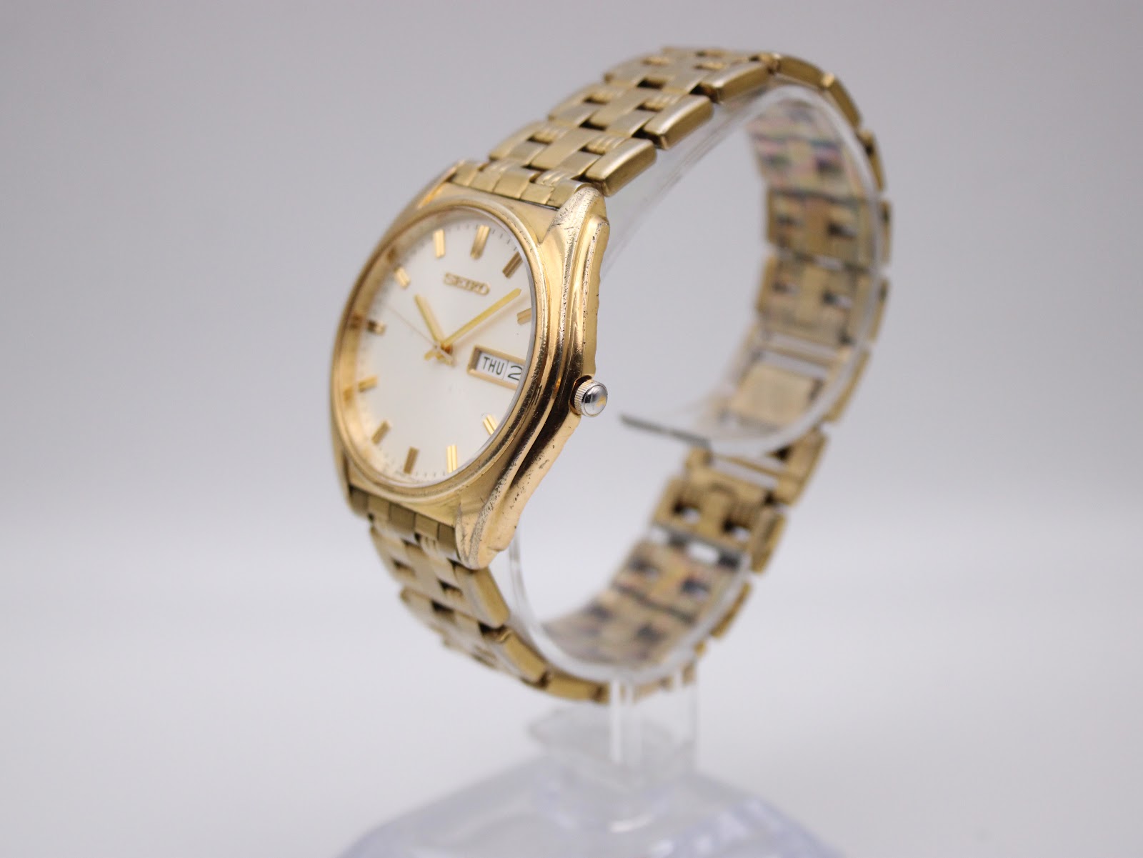 Angled side view of the Seiko V743-8069 watch on a clear display stand, showing the crown and case profile.