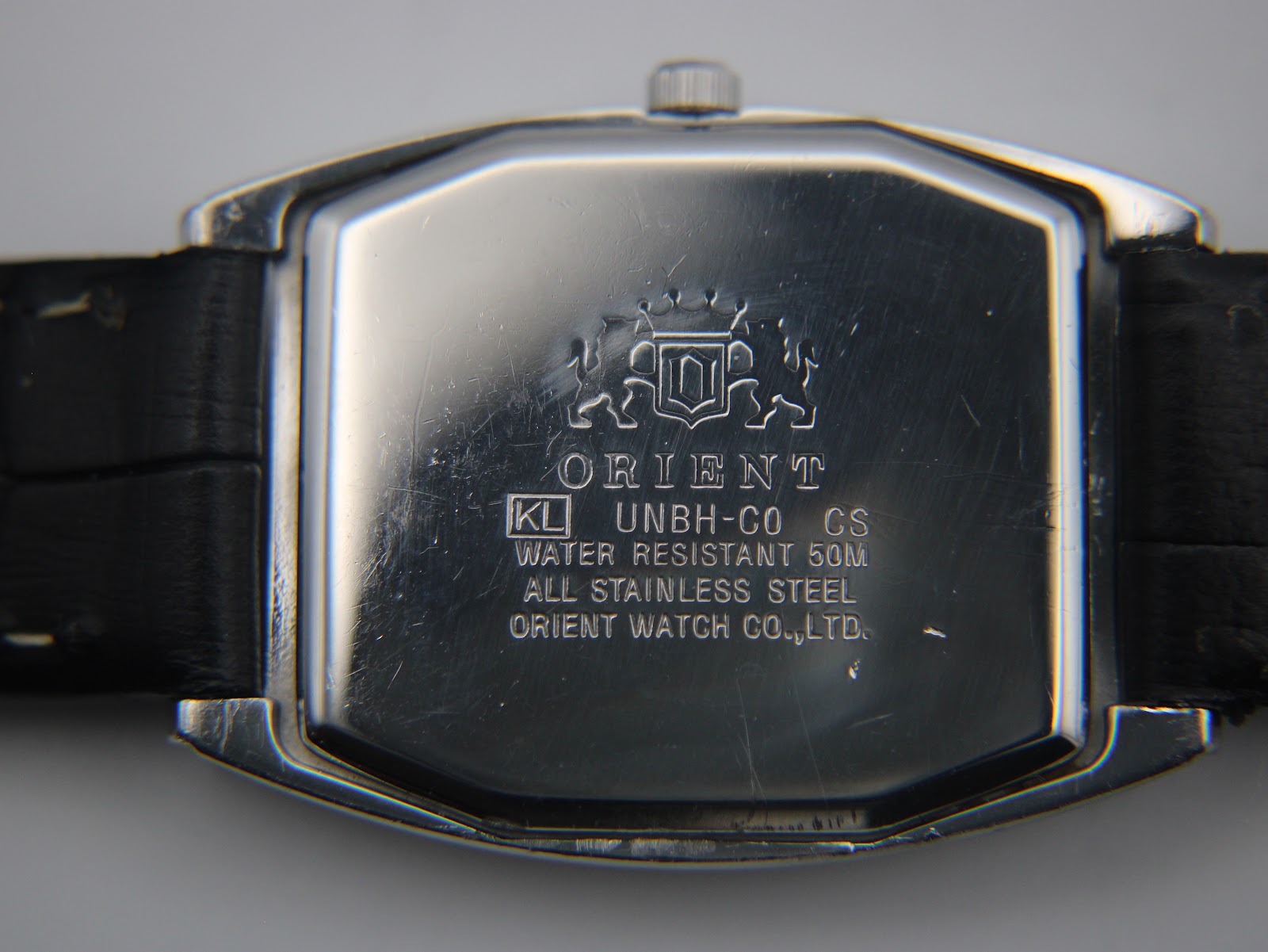 Close-up of the stainless steel case back of the Orient UNBH-CO watch, showing brand, model, water resistance (50M), and "All Stainless Steel" engravings.