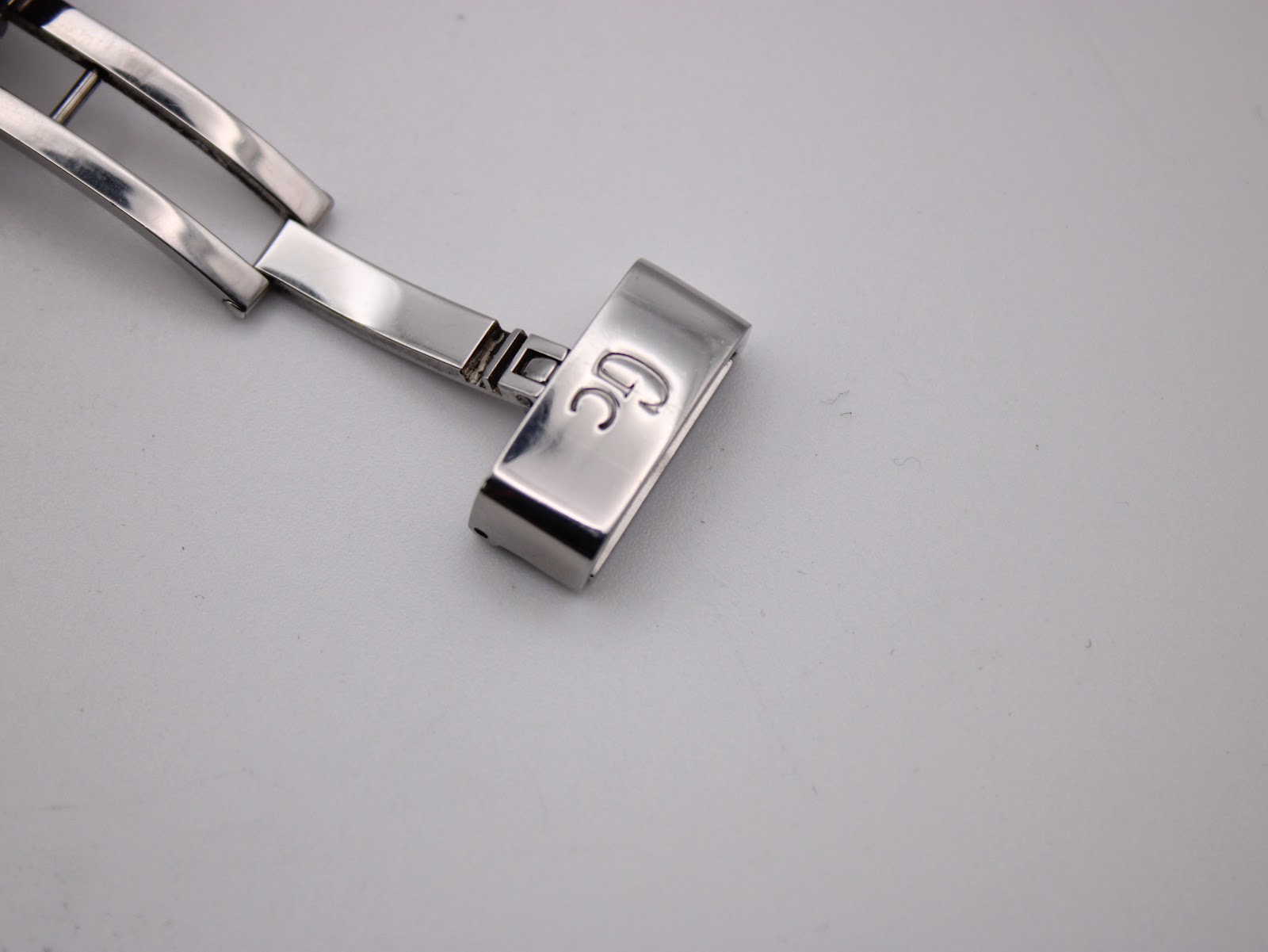 Close-up of the polished silver-tone deployant clasp with "Gc" logo engraved.