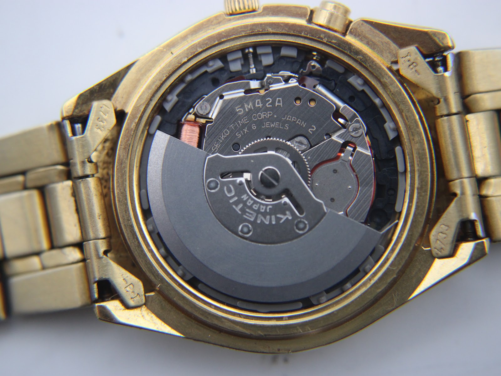 Close-up internal view of the Seiko 5M42A Kinetic movement with rotor visible, showing "JAPAN 2 SIX 6 JEWELS".
