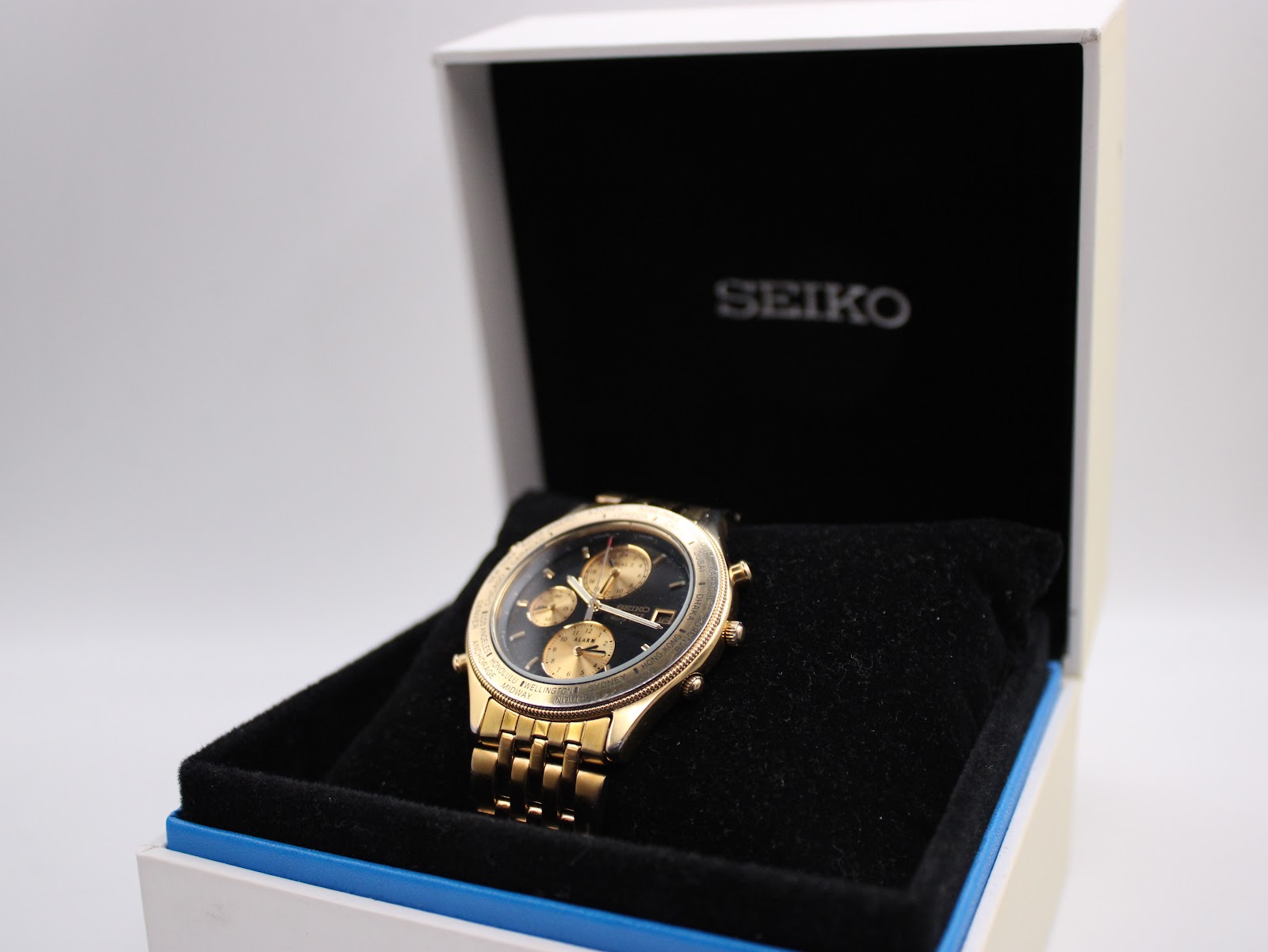 Angled view of the gold-tone Seiko 5T52-7A2A world timer watch in its original black and white Seiko box.