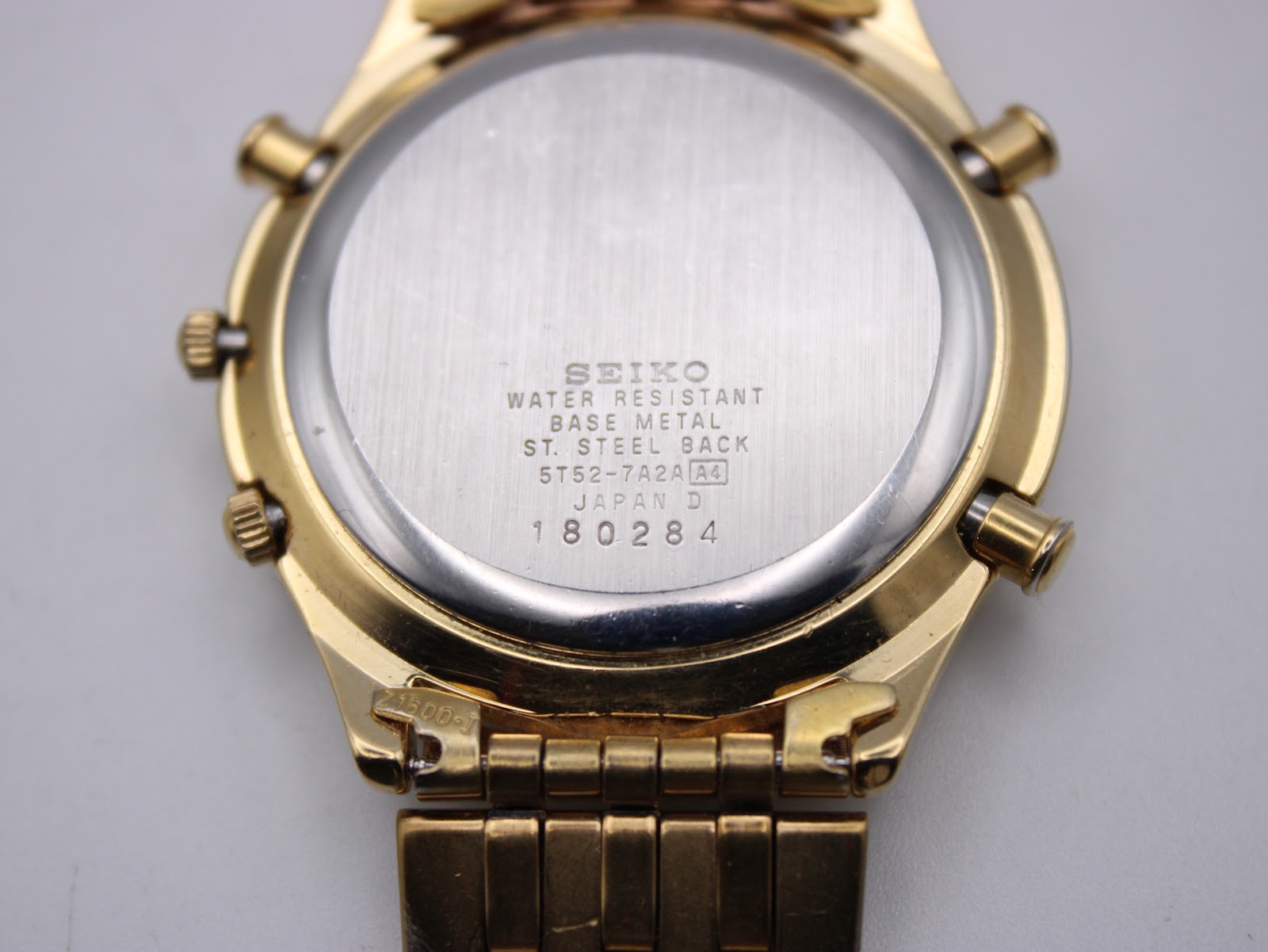 Close-up of the watch case back, showing "SEIKO WATER RESISTANT BASE METAL ST. STEEL BACK 5T52-7A2A A4 JAPAN D 180284".