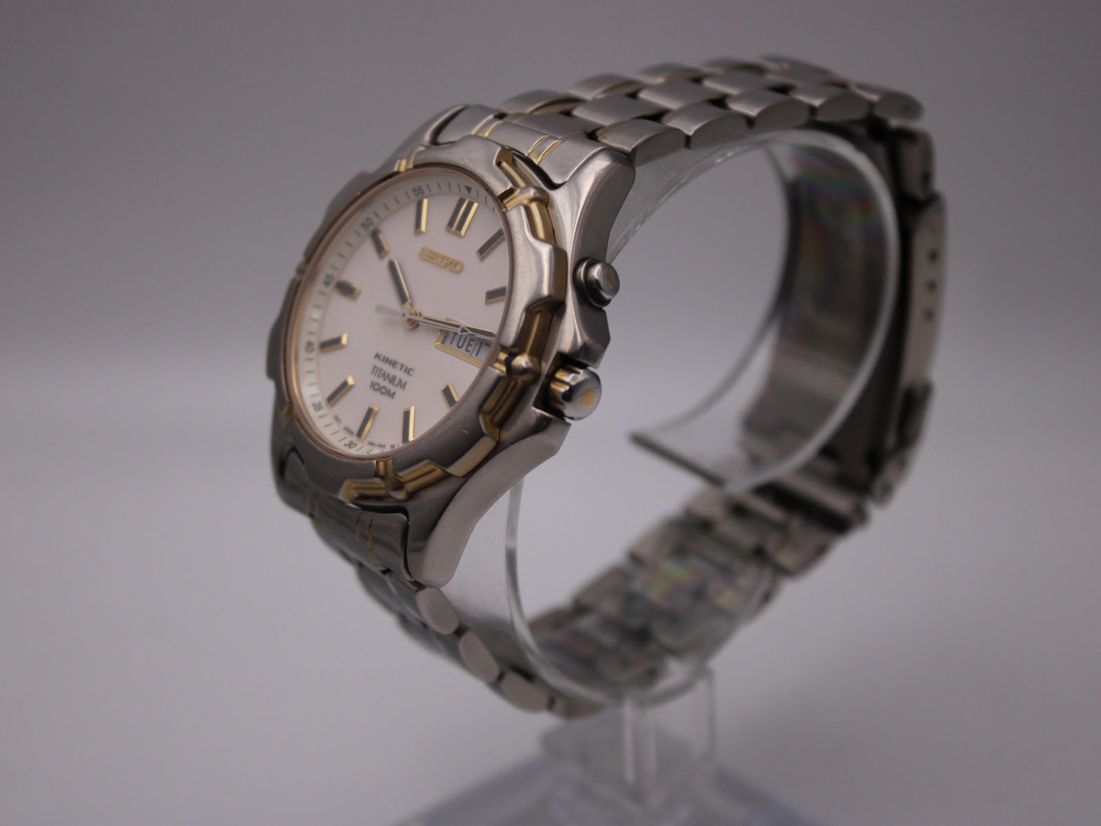 Three-quarter angled view of the Seiko Kinetic watch on a display stand, highlighting the two-tone titanium case and integrated bracelet.