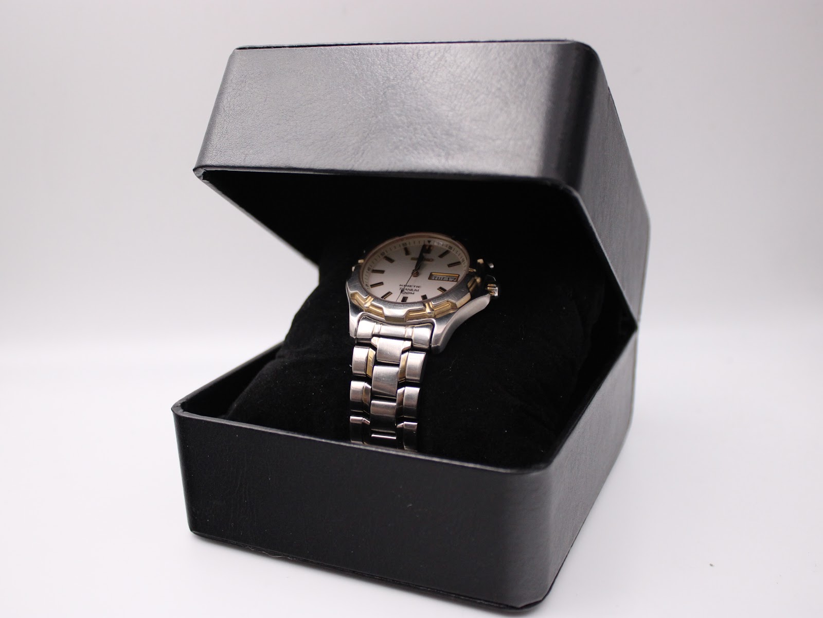 The two-tone Seiko Kinetic watch displayed neatly inside a generic black presentation watch box on a cushion.