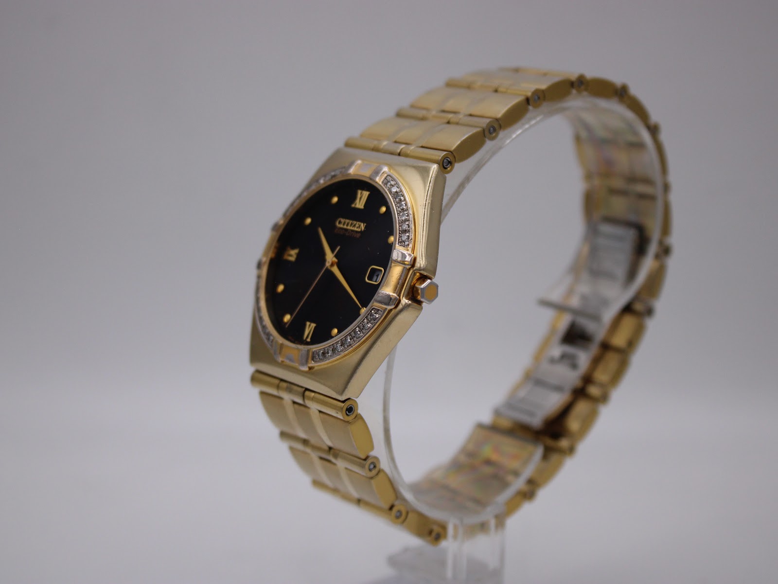 Angled side view of the Citizen Eco-Drive watch on a clear stand, showing the bracelet and clasp.