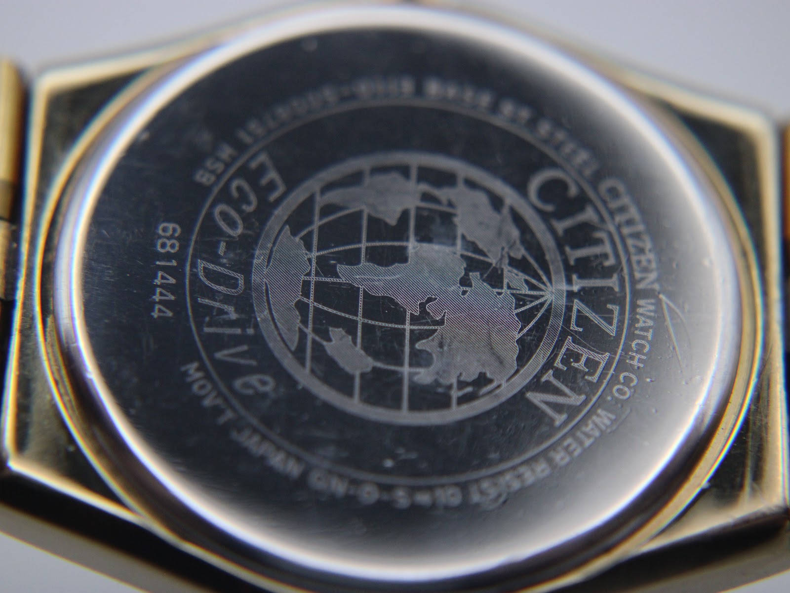 Close-up of the Citizen Eco-Drive watch case back, showing 'Eco-Drive', '681444', 'Base St. Steel', and globe logo.
