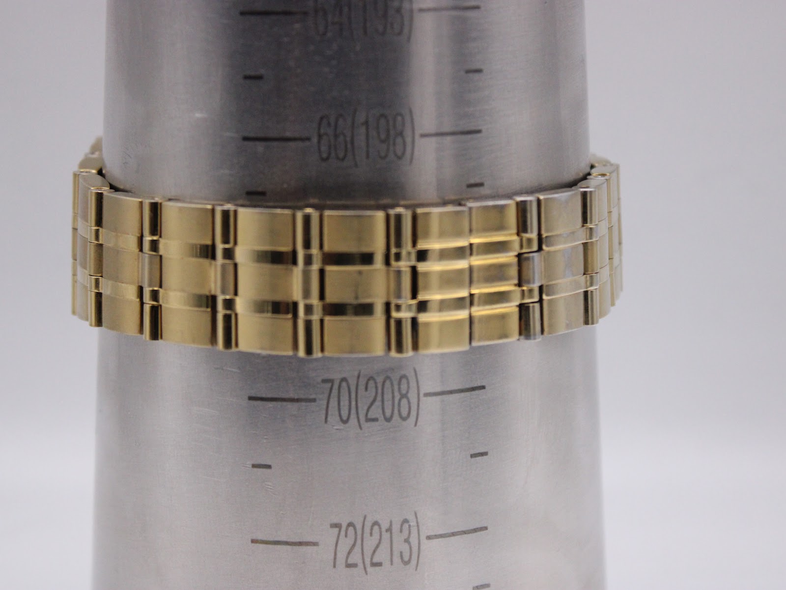 The gold-tone bracelet of the Citizen Eco-Drive watch on a wrist sizing gauge, showing approximately 203mm.