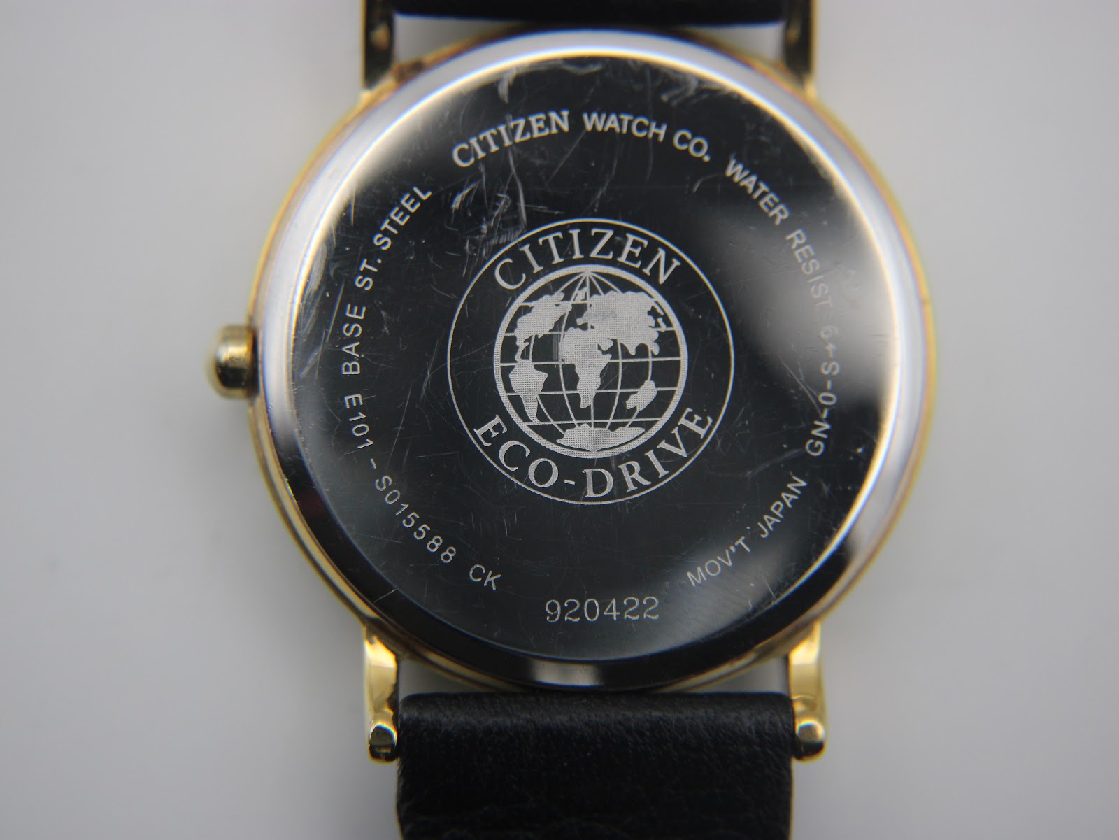 Close-up of the stainless steel case back of the Citizen watch, showing 'Citizen Watch Co. Water Resist Base St. Steel Eco-Drive' engravings and serial number 920422, with some surface scratches.
