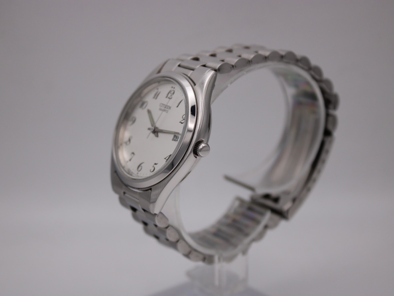 Side profile view of the Citizen watch on a clear display stand, showing the crown and the curved case design.