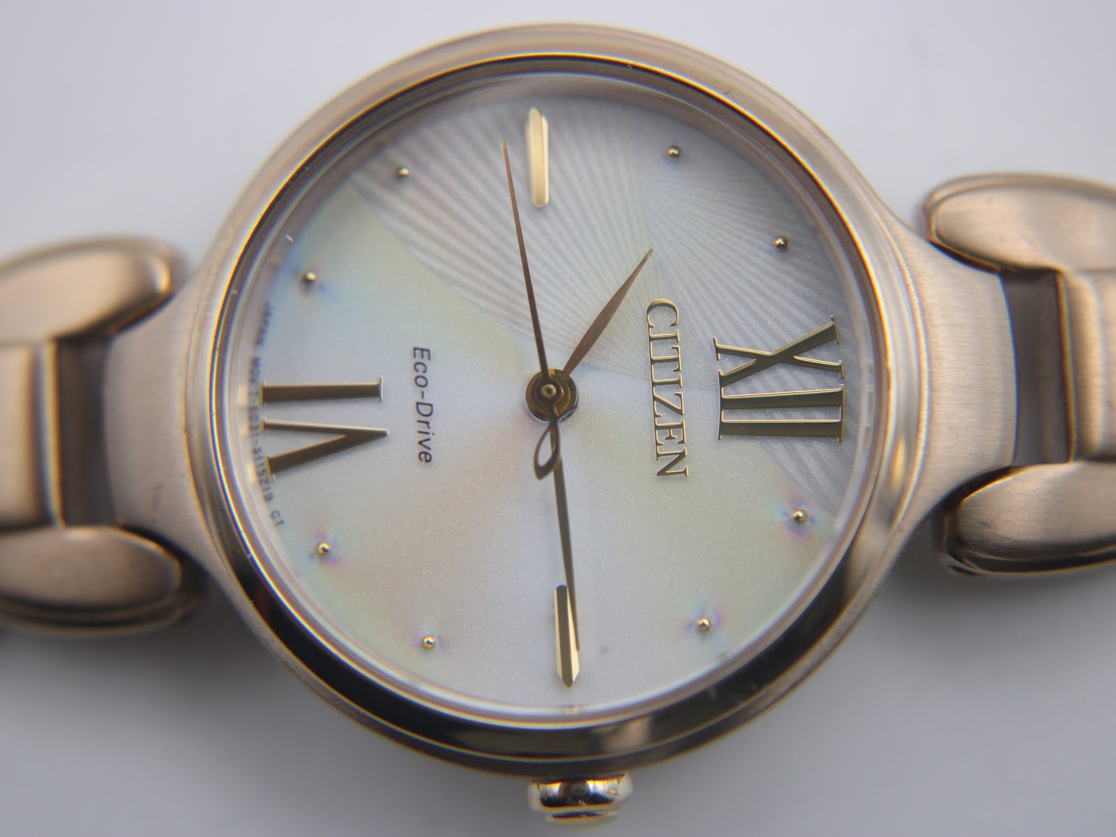 Detailed close-up of the iridescent mother-of-pearl dial of the Citizen Eco-Drive, with rose gold tone Roman numerals and baton indices.