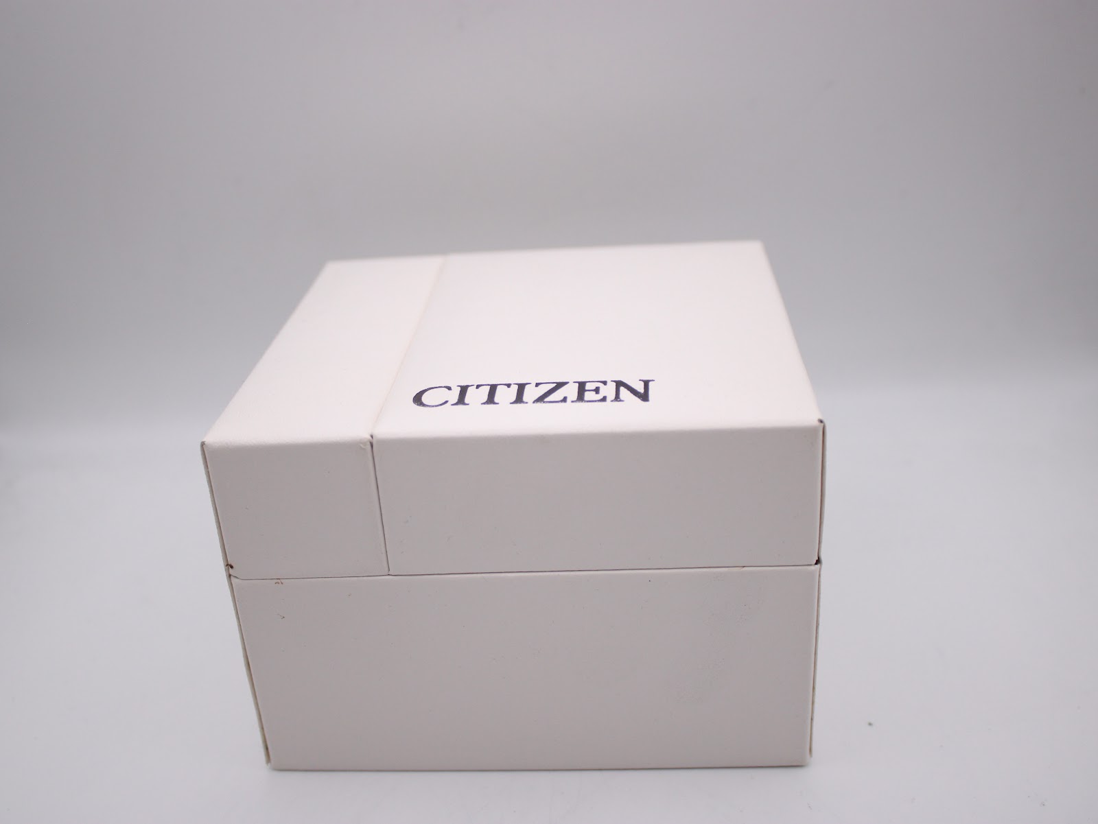 The closed original white Citizen watch box with the brand name printed on the lid.