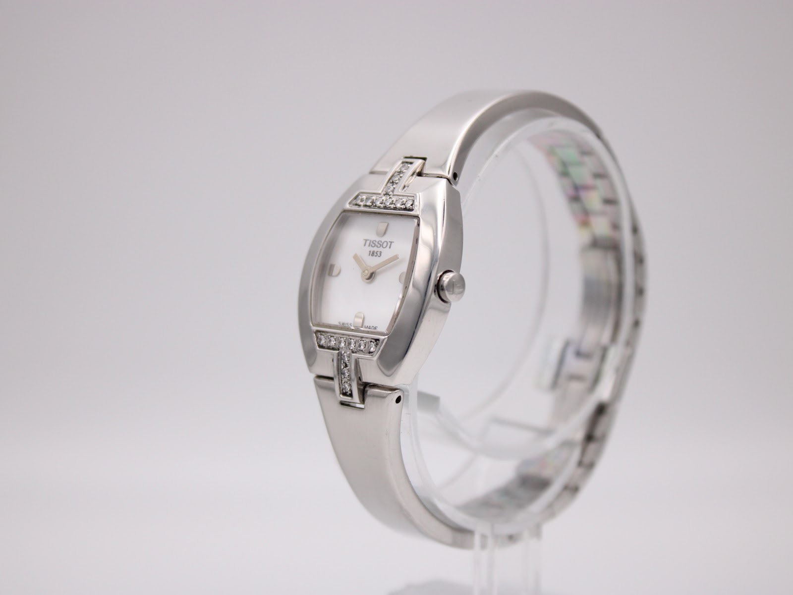 Angled side view of the Tissot L953 watch on a display stand, showing the tonneau case and bracelet.