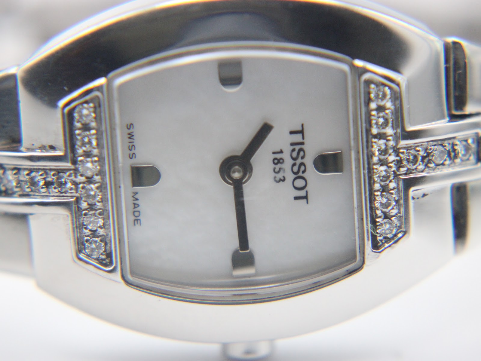 Detailed close-up of the mother of pearl dial, showing the Tissot logo, simple indices, and diamond accents on the case.