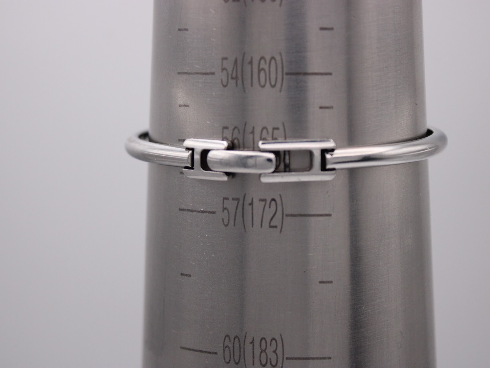 Rear view of the Gucci 1900 L bangle bracelet on a wrist sizing cone, showing the concealed clasp and wrist measurement lines.