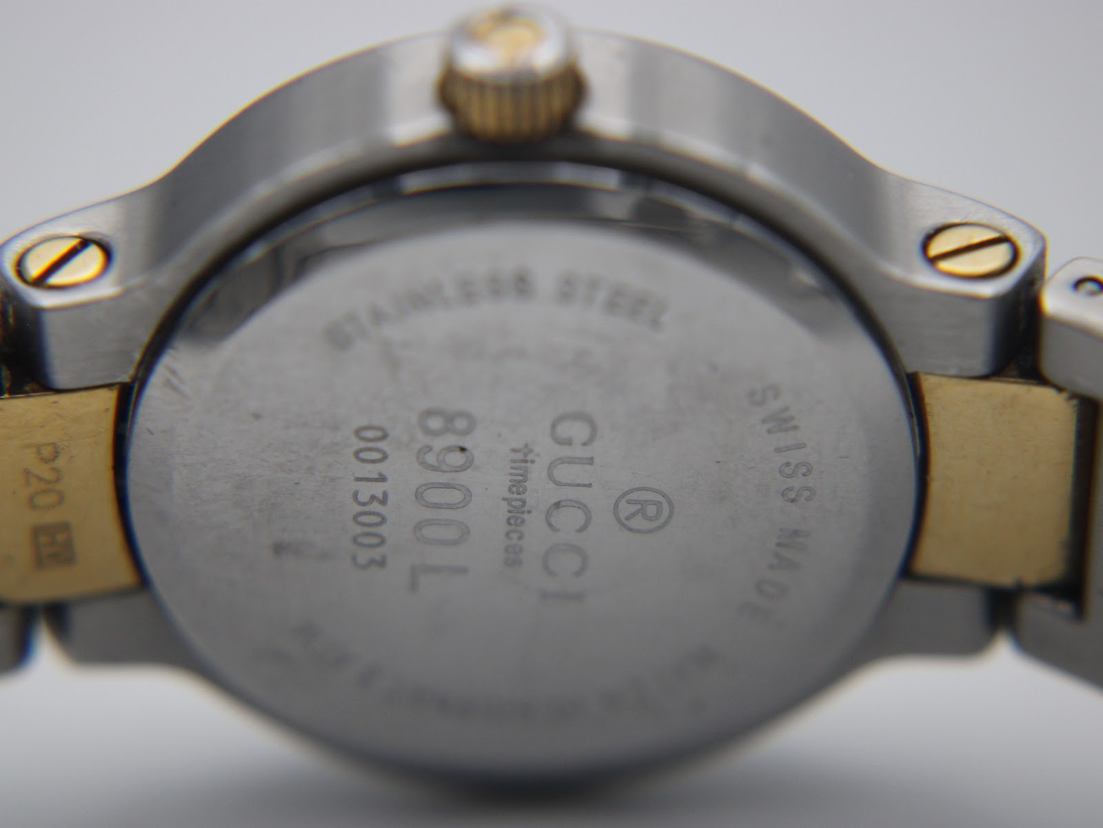 Close-up of the watch case back, showing "Gucci Timepieces," "8900L," "0013003," and "Stainless Steel Swiss Made."
