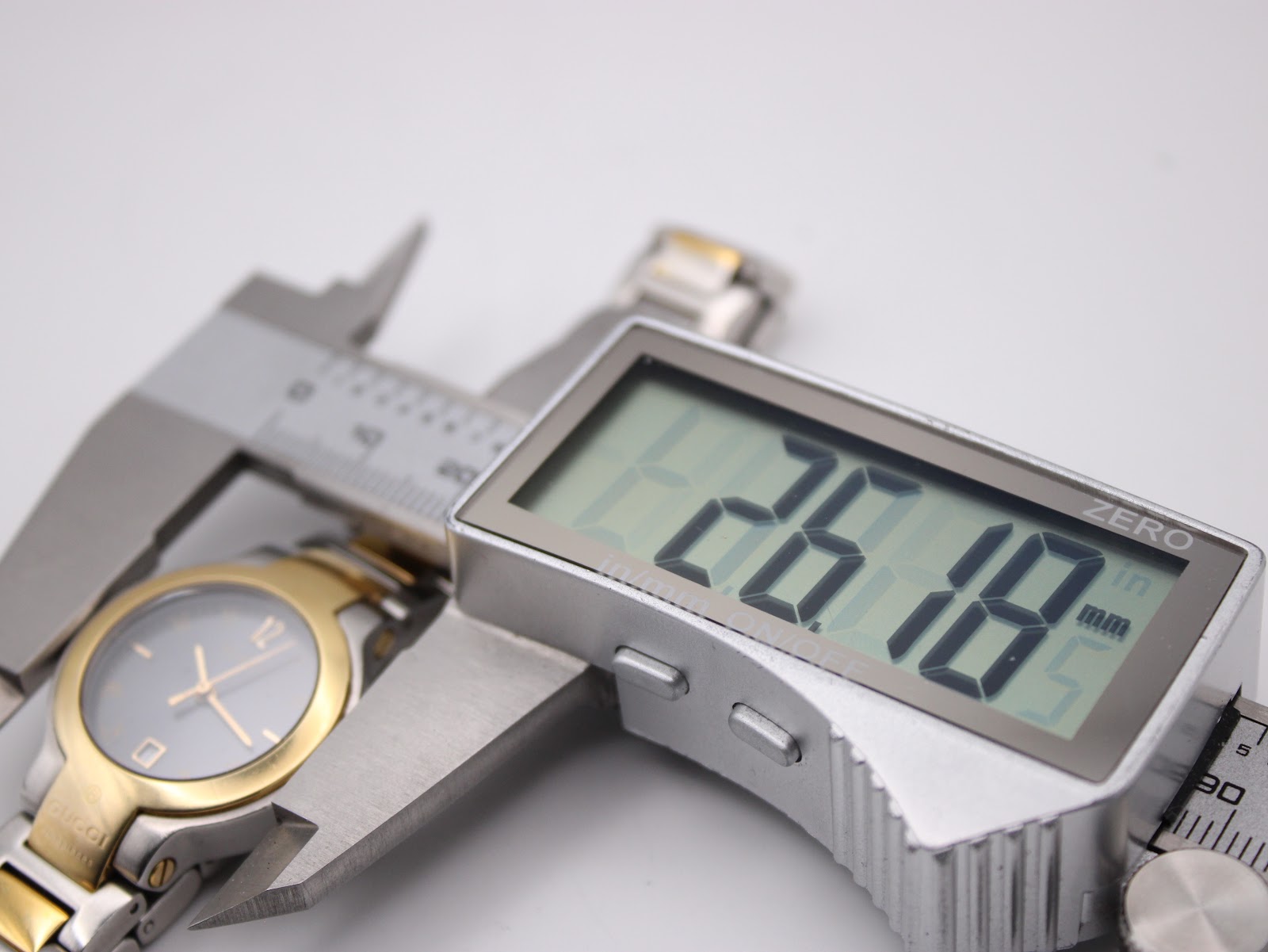 Digital caliper measuring the watch case diameter at 26.18mm.